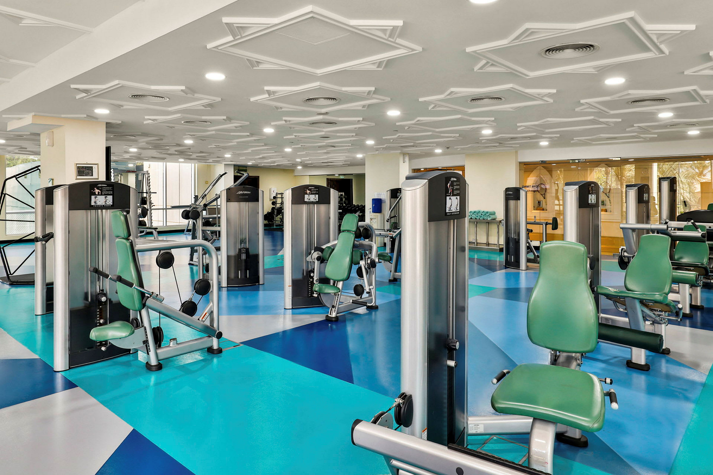 Et fitnesscenter med træningsmaskiner og grønne sæder. (AI-genereret tekst)