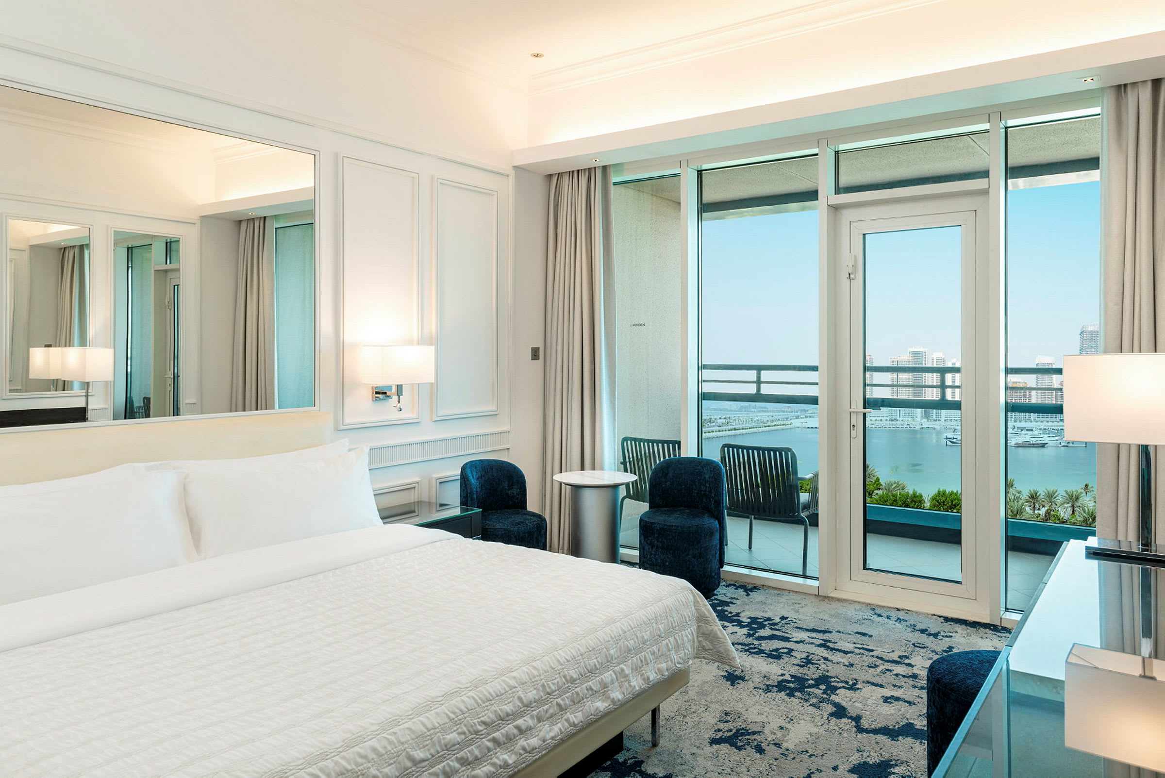 Hotelværelse med redt seng, moderne indretning og balkon med udsigt over havet. (AI-genereret tekst)