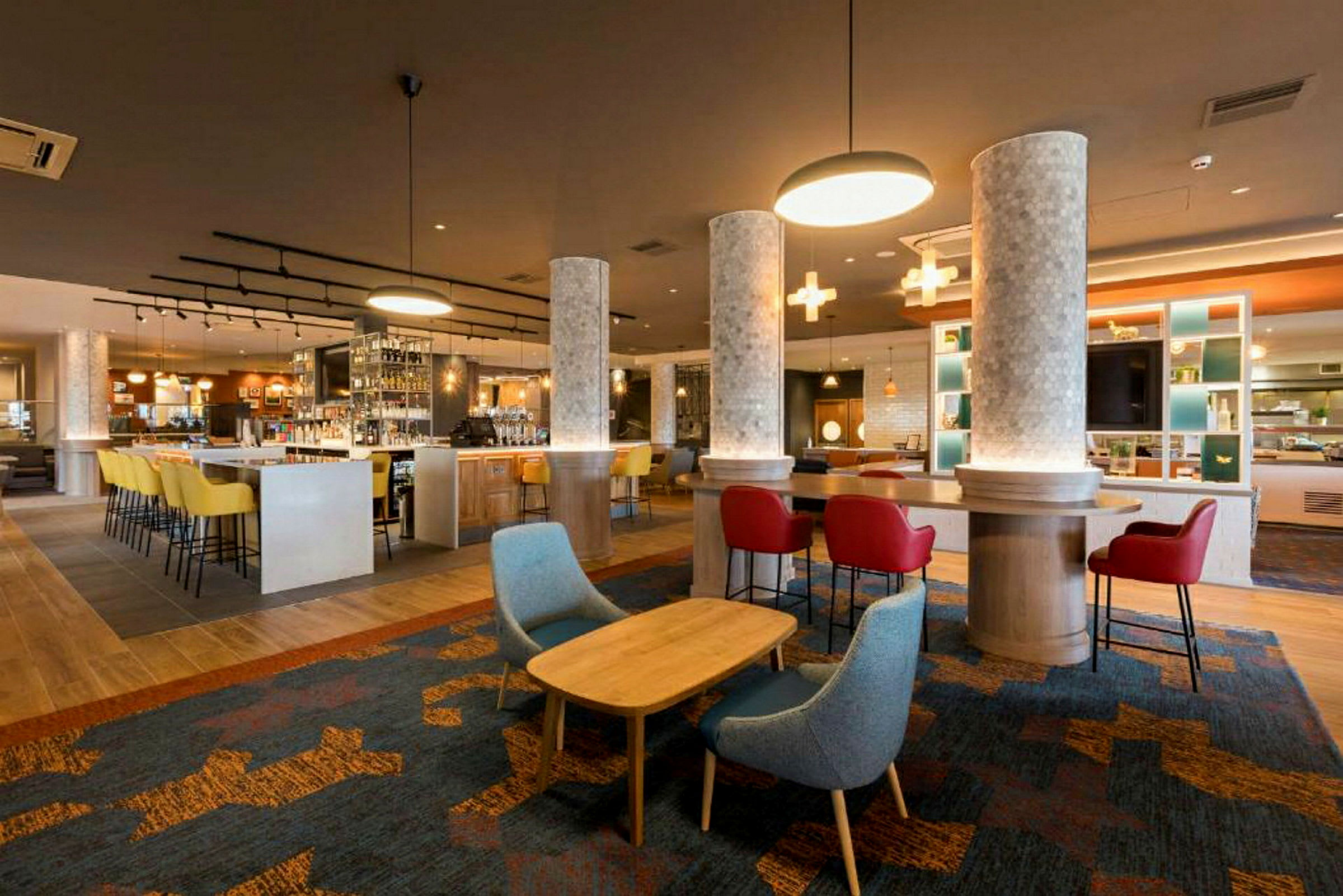 En moderne hotelbar med farverige stole og belysning. (AI-genereret tekst)
