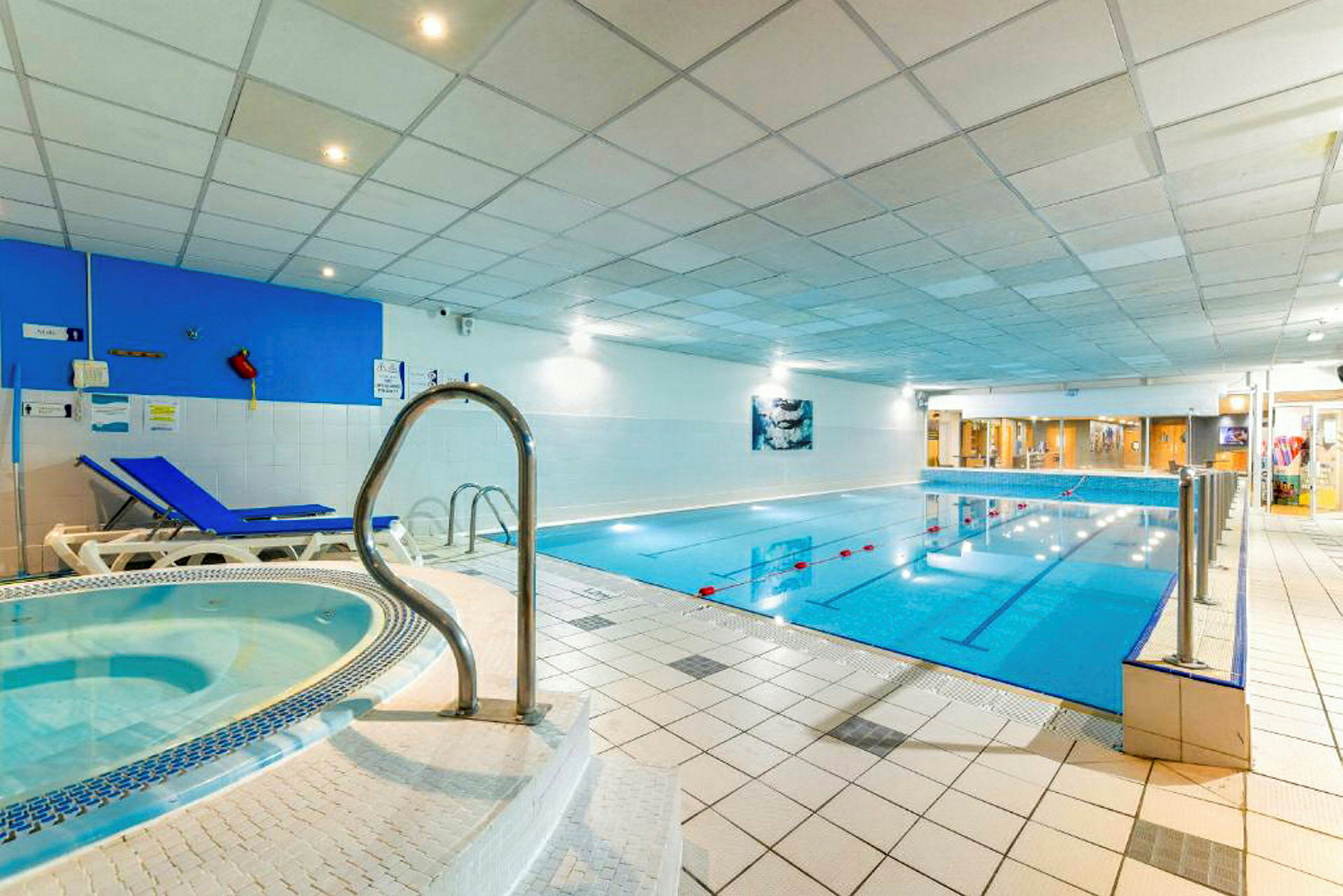 Indendørs poolområde med en jacuzzi og liggestole. (AI-genereret tekst)