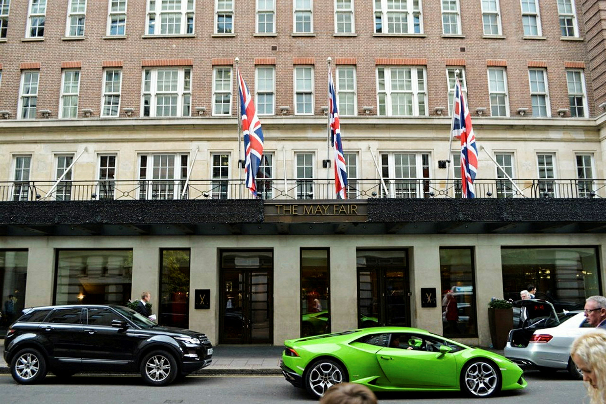 Facade af det elegante May Fair Hotel med biler parkeret foran. (AI-genereret tekst)