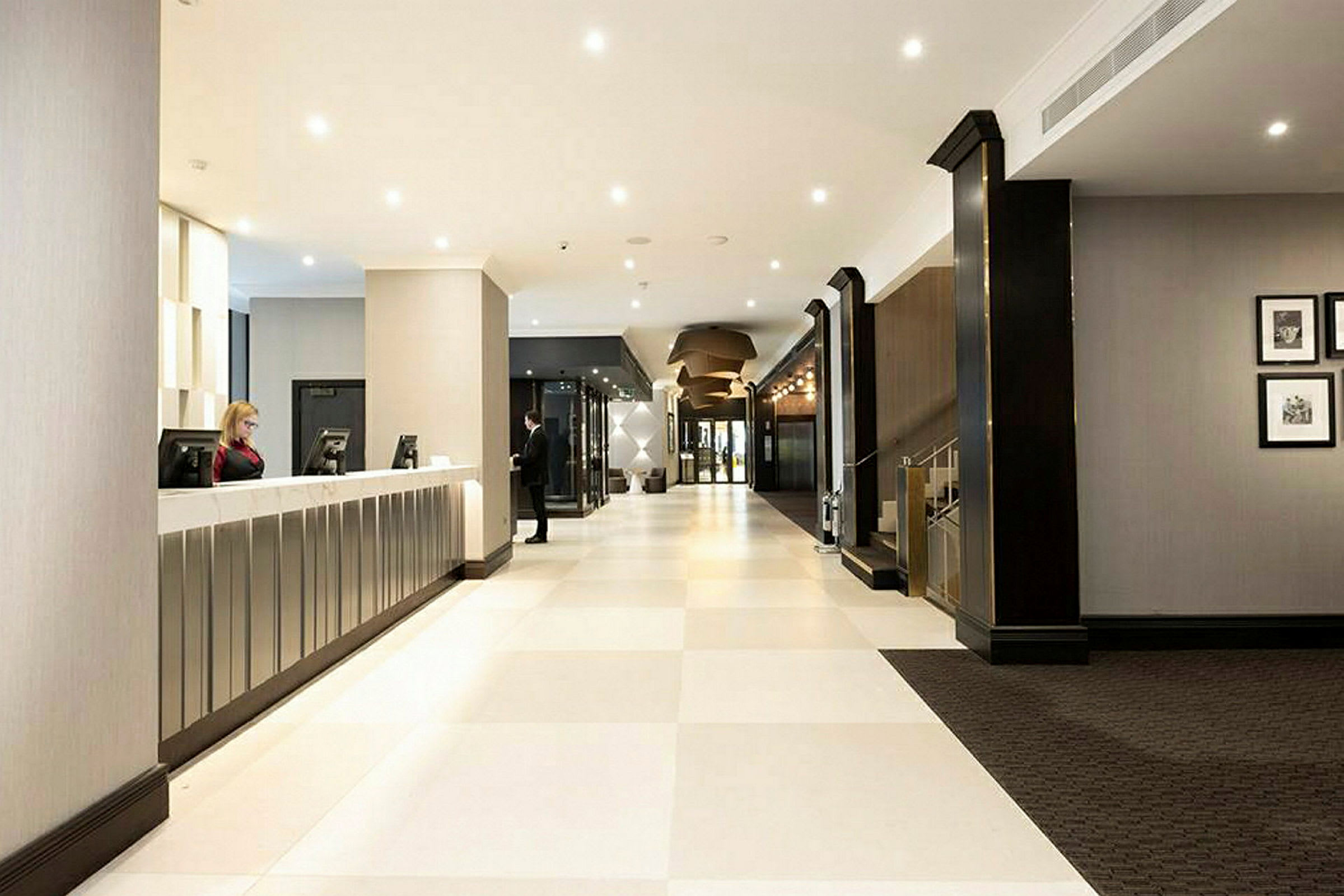 Hotellobby med receptionsskranke og lyse gulve. (AI-genereret tekst)