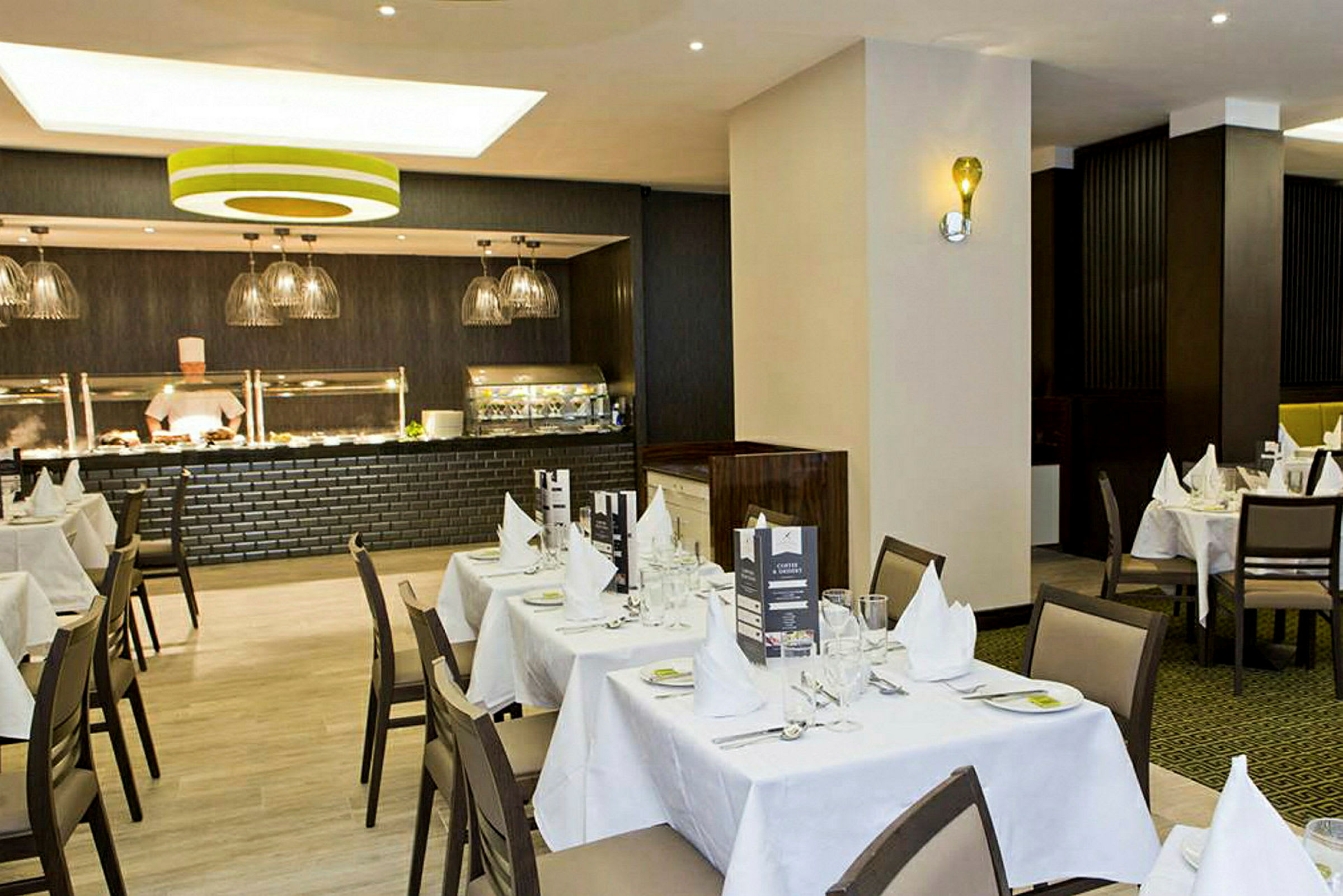 Restaurant med dækkede borde og en buffetskranke. (AI-genereret tekst)
