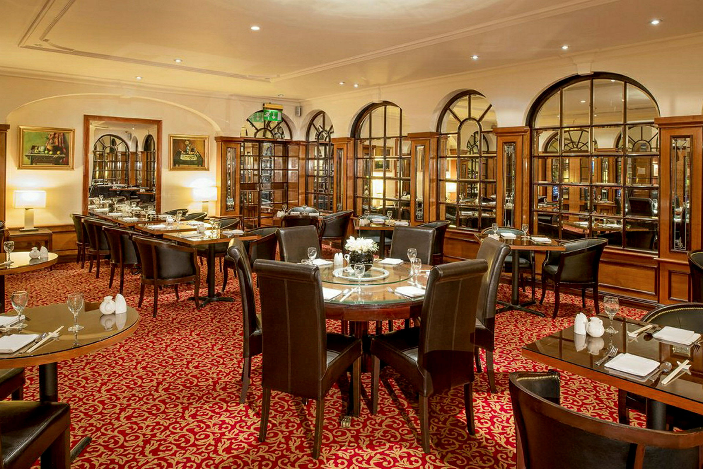 Restaurant med opdækkede borde og stole, elegant indretning med spejlvægge og røde tæpper. (AI-genereret tekst)