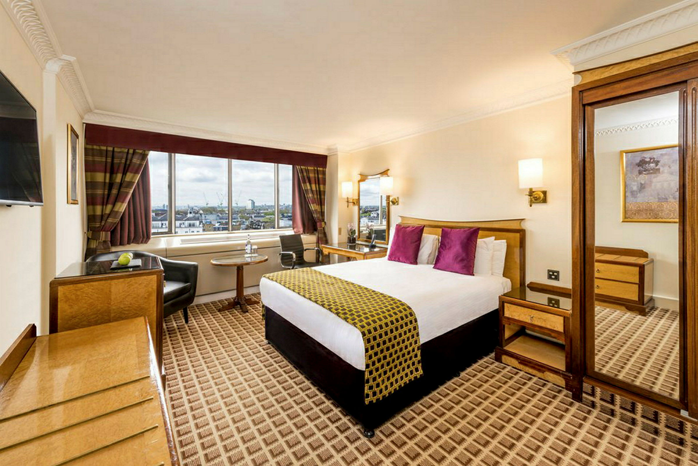 Hotelværelse med stor seng, vindue med udsigt og møbler. (AI-genereret tekst)
