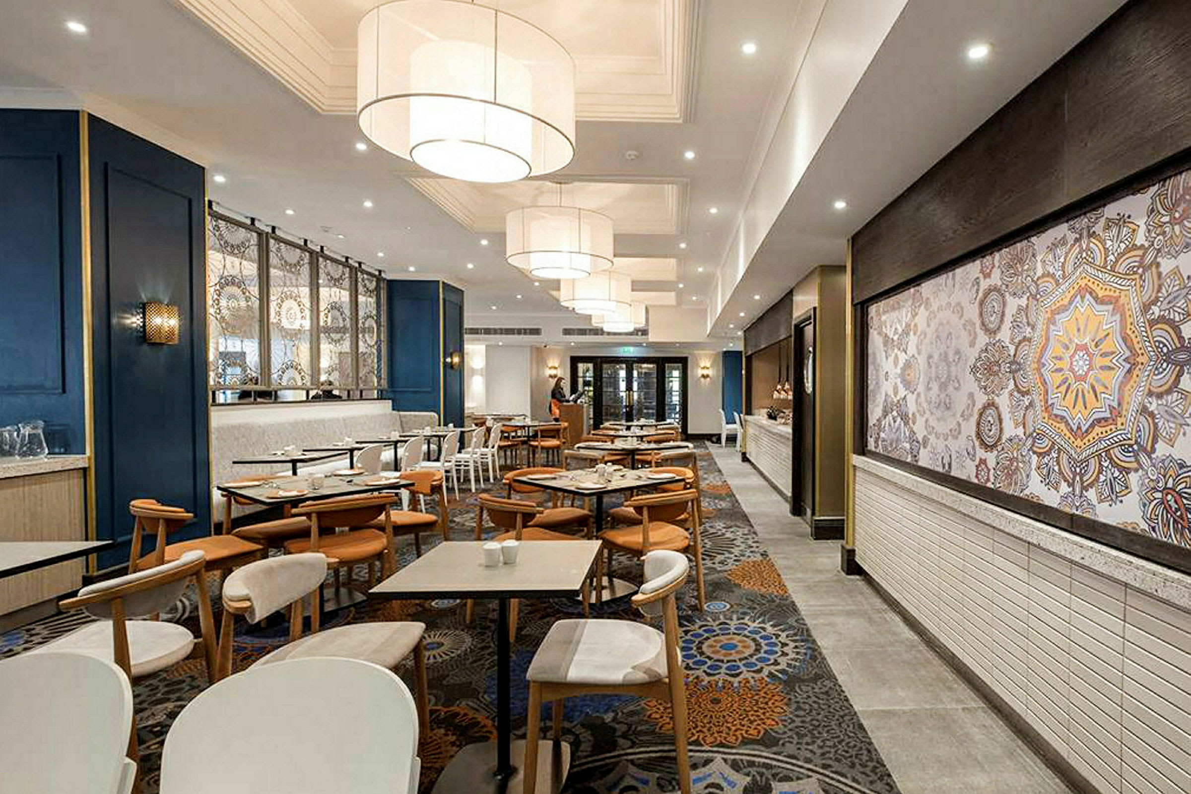 En restaurant med borde og stole, moderne indretning og store lamper i loftet. (AI-genereret tekst)