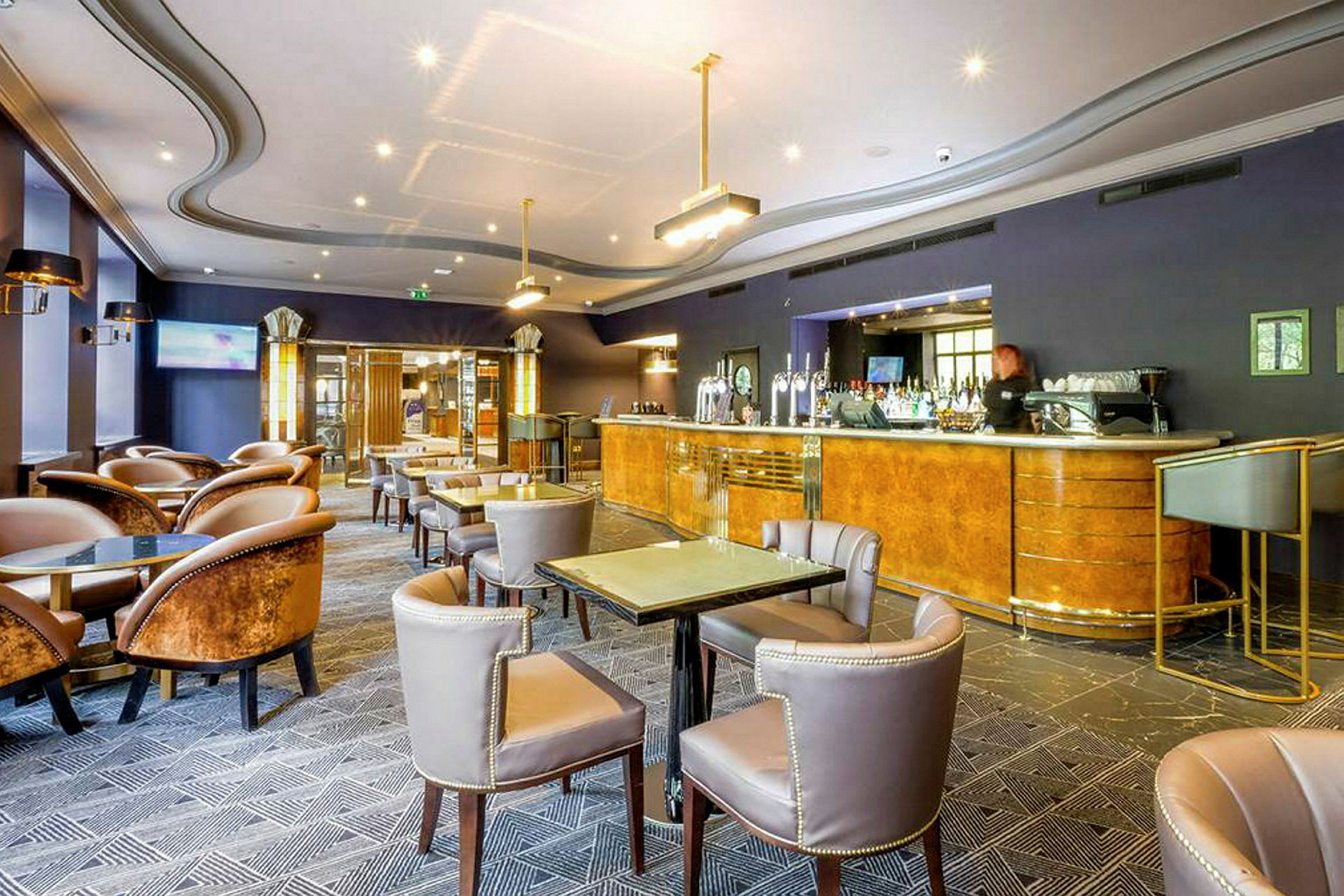 En hotelbar med borde og stole samt en bardisk. (AI-genereret tekst)