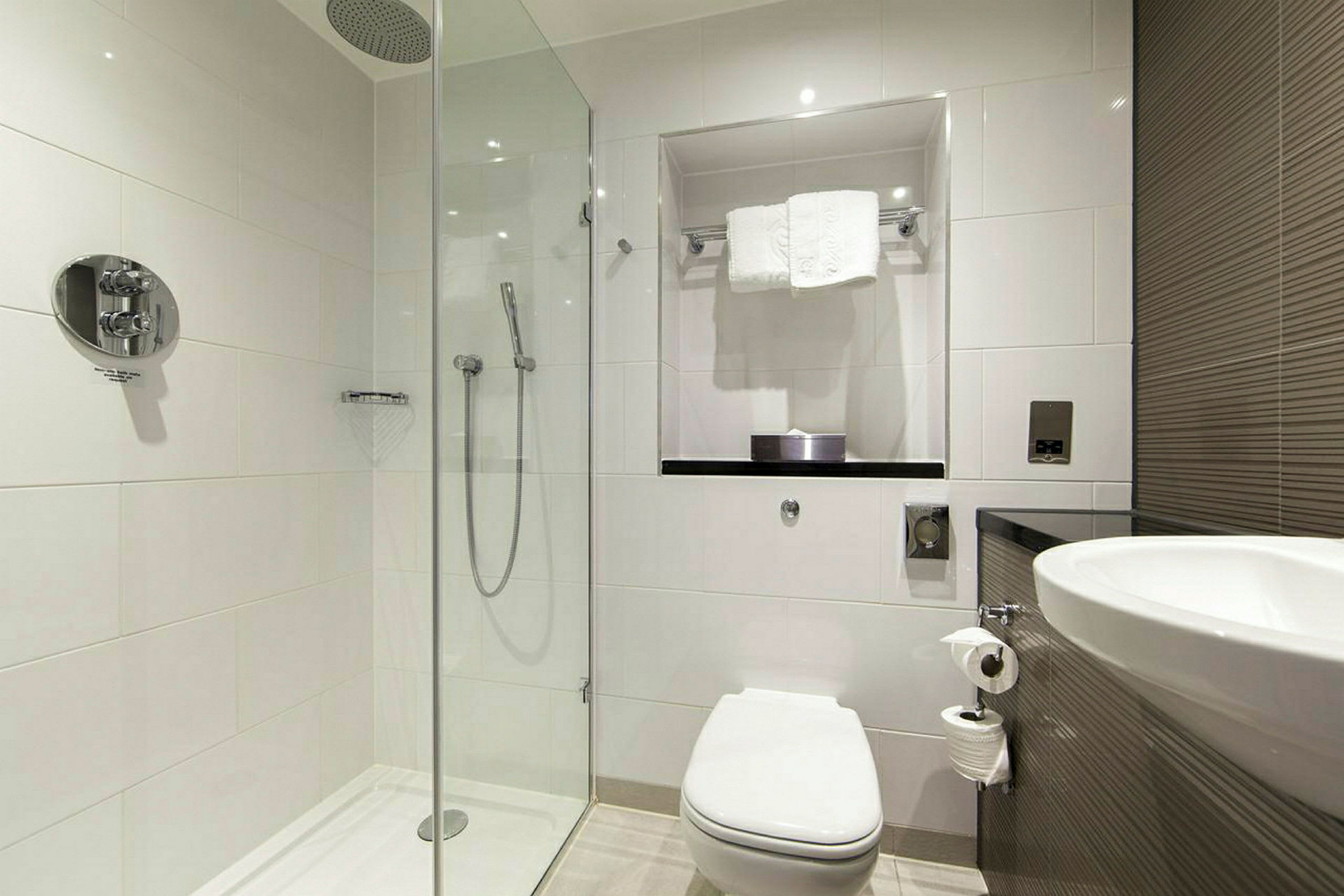Moderne badeværelse med bruseområde, toilet og vask. (AI-genereret tekst)