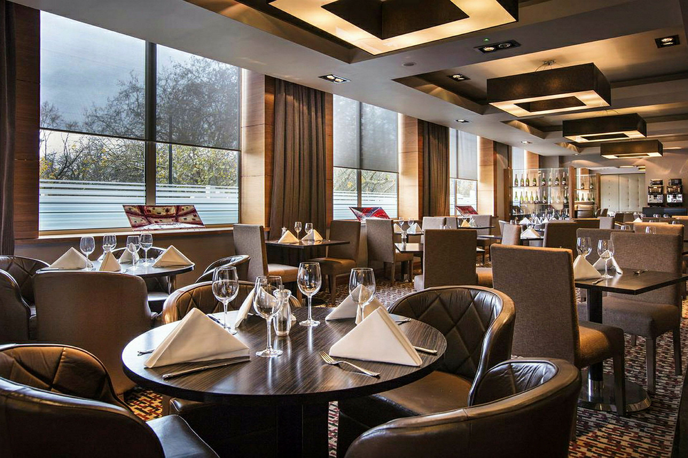 En elegant restaurant med dækkede borde med hvide servietter og vinglas. (AI-genereret tekst)