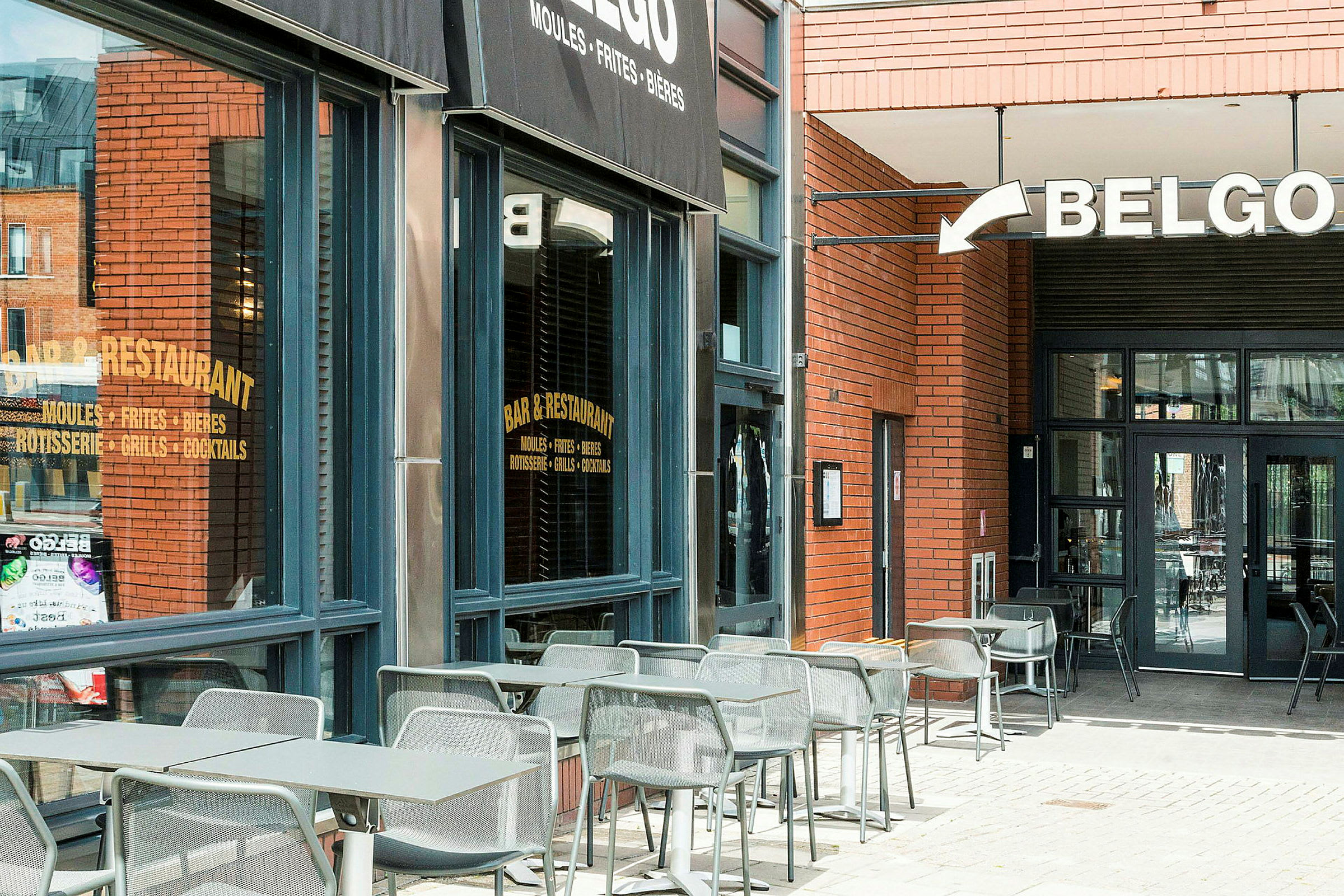 Udendørsservering ved en restaurant med et skilt der lyder 'Belgo'. (AI-genereret tekst)