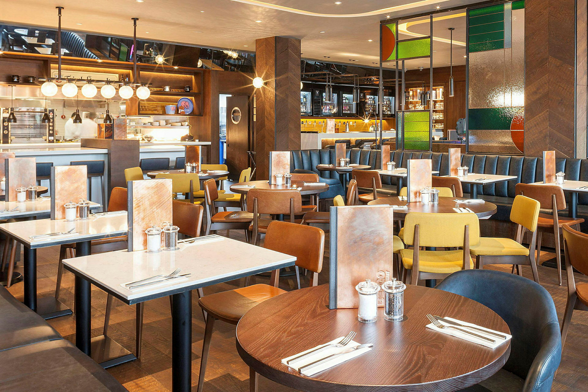 Restaurant med flere spiseborde og stole i forskellige farver. (AI-genereret tekst)