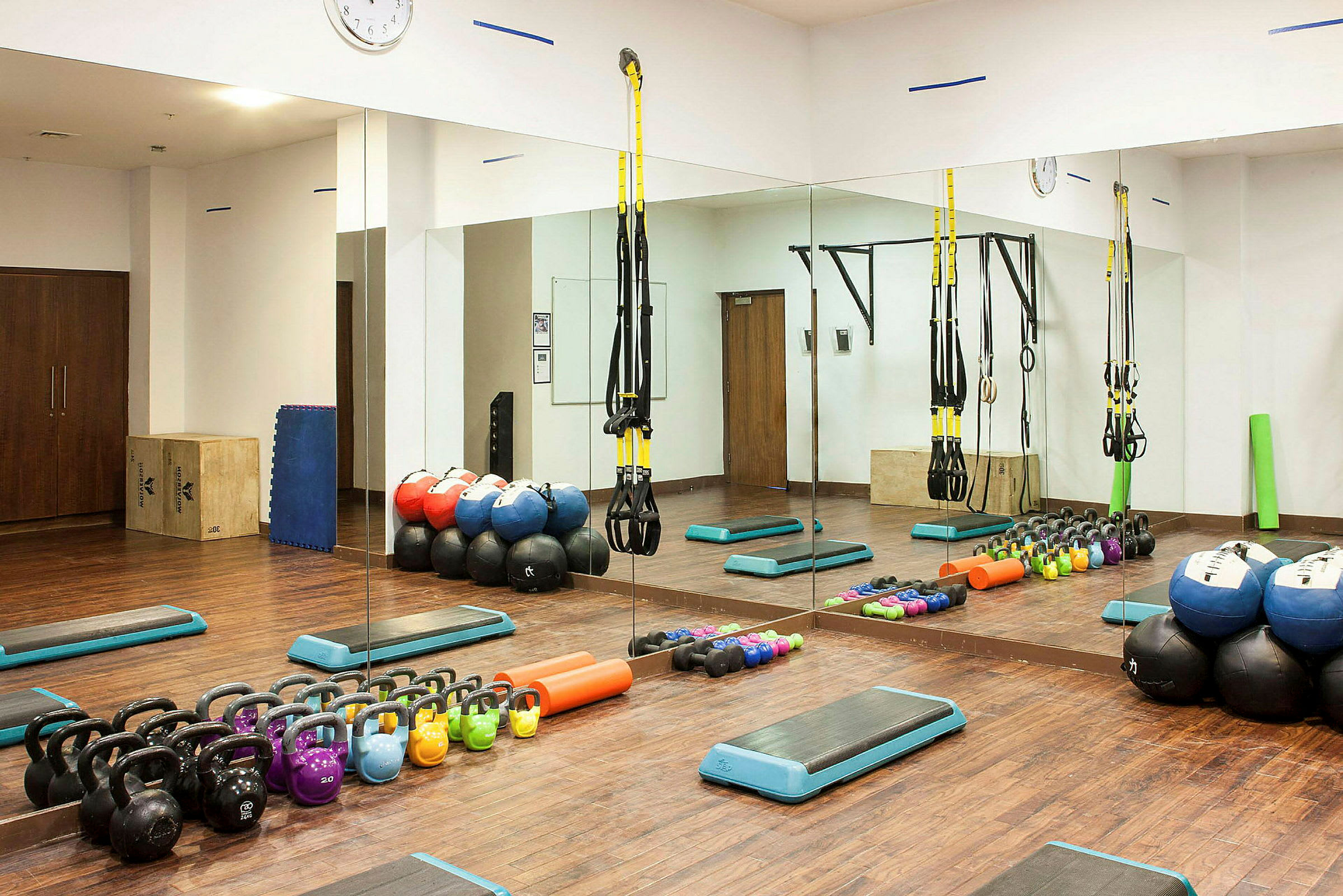 Et træningsrum med fitnessudstyr som kettlebells, medicinbolde og remme. (AI-genereret tekst)