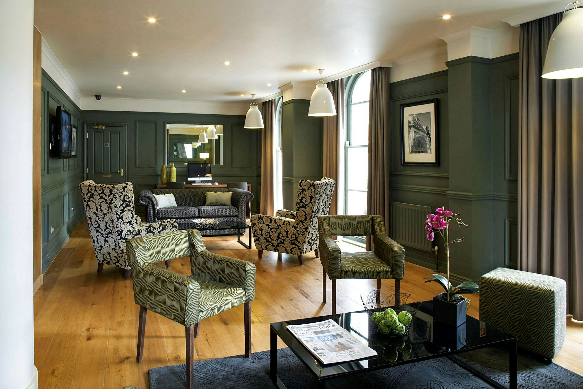 Et elegant hotellets loungeområde med lænestole og sofaer, pynteplanter og moderne indretning. (AI-genereret tekst)