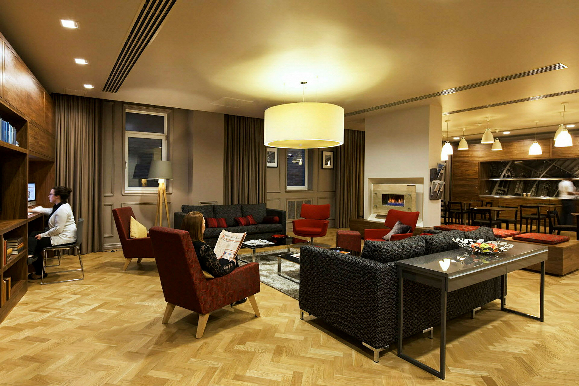 Et elegant opholdsområde med sofaer, lænestole og et sofabord omgivet af varm belysning og moderne indretning. (AI-genereret tekst)