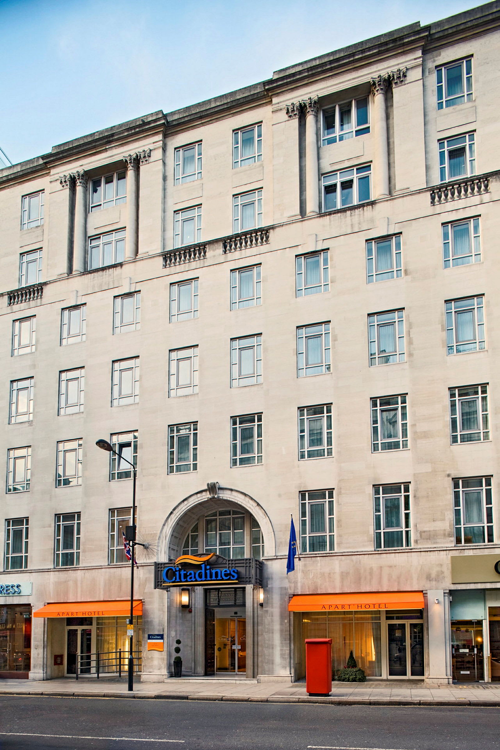 En bygning med flere etager med navnet Citadines og indgange til et hotel og butikker. (AI-genereret tekst)