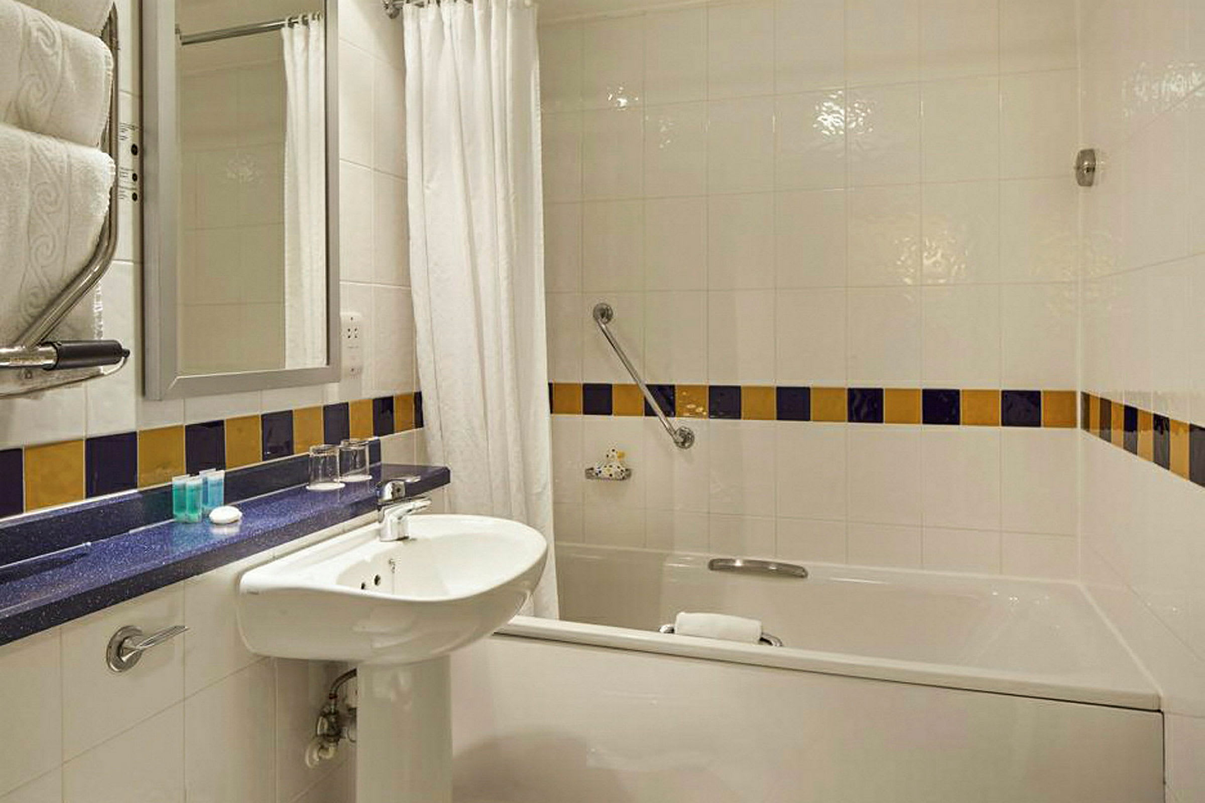 Hotelbadeværelse med badekar, håndvask og spejl. (AI-genereret tekst)