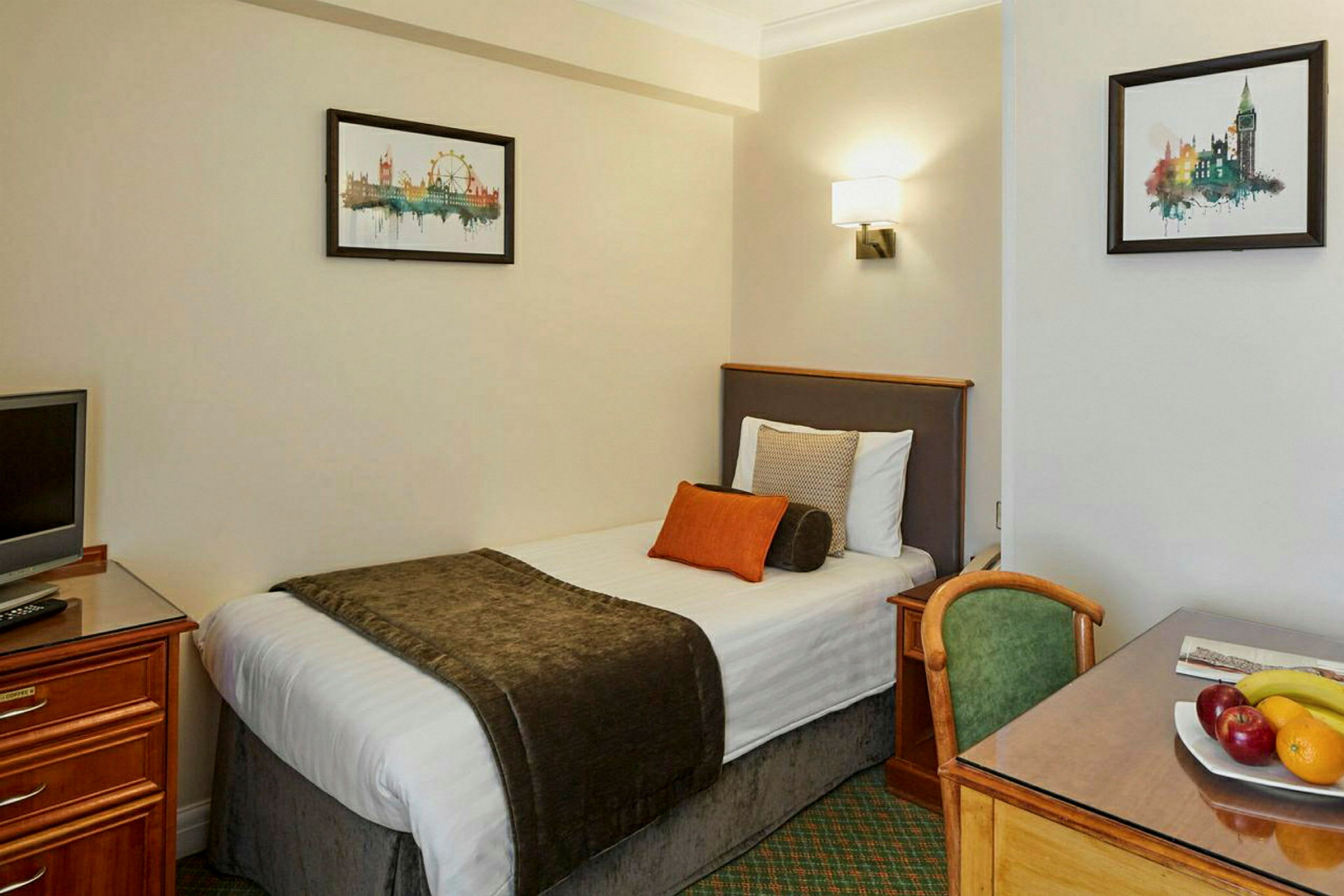 Hotelværelse med enkeltseng, skrivebord, stol og dekorativ kunst på væggen. (AI-genereret tekst)