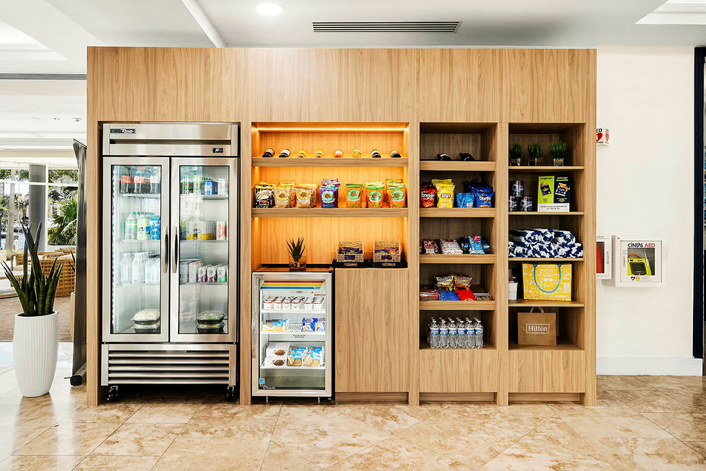 En moderne kiosk med et køleskab, hylder med snacks og drikkevarer samt andre handelsvarer. (AI-genereret tekst)