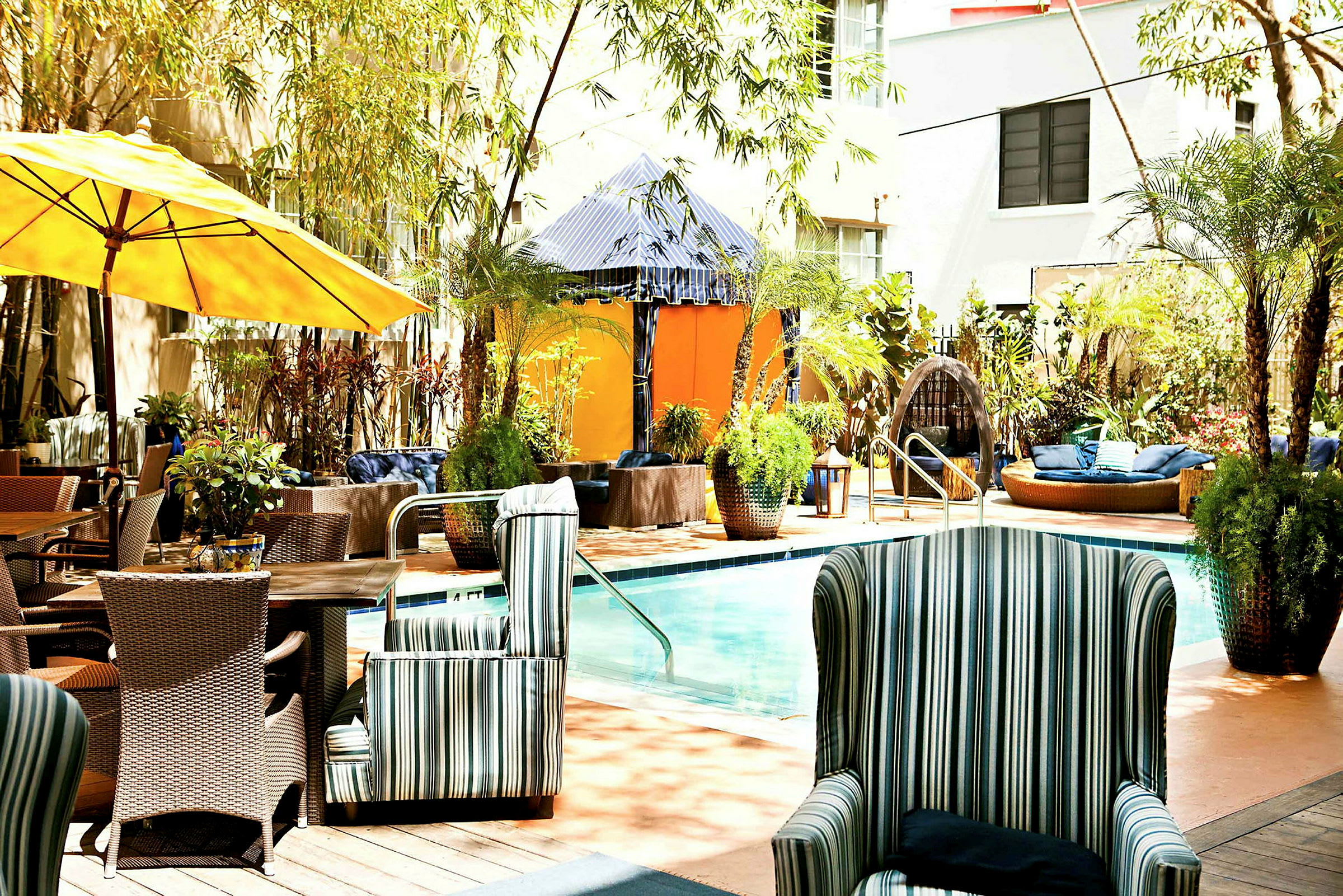 En udendørs terrasse med pool, omgivet af grønne planter og komfortable siddepladser. (AI-genereret tekst)