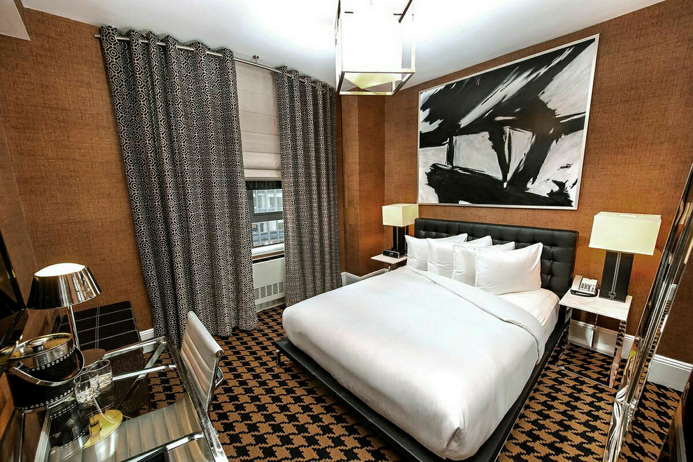 Hotelværelse med moderne indretning, en stor seng, skrivebord og abstrakt kunst på væggen. (AI-genereret tekst)