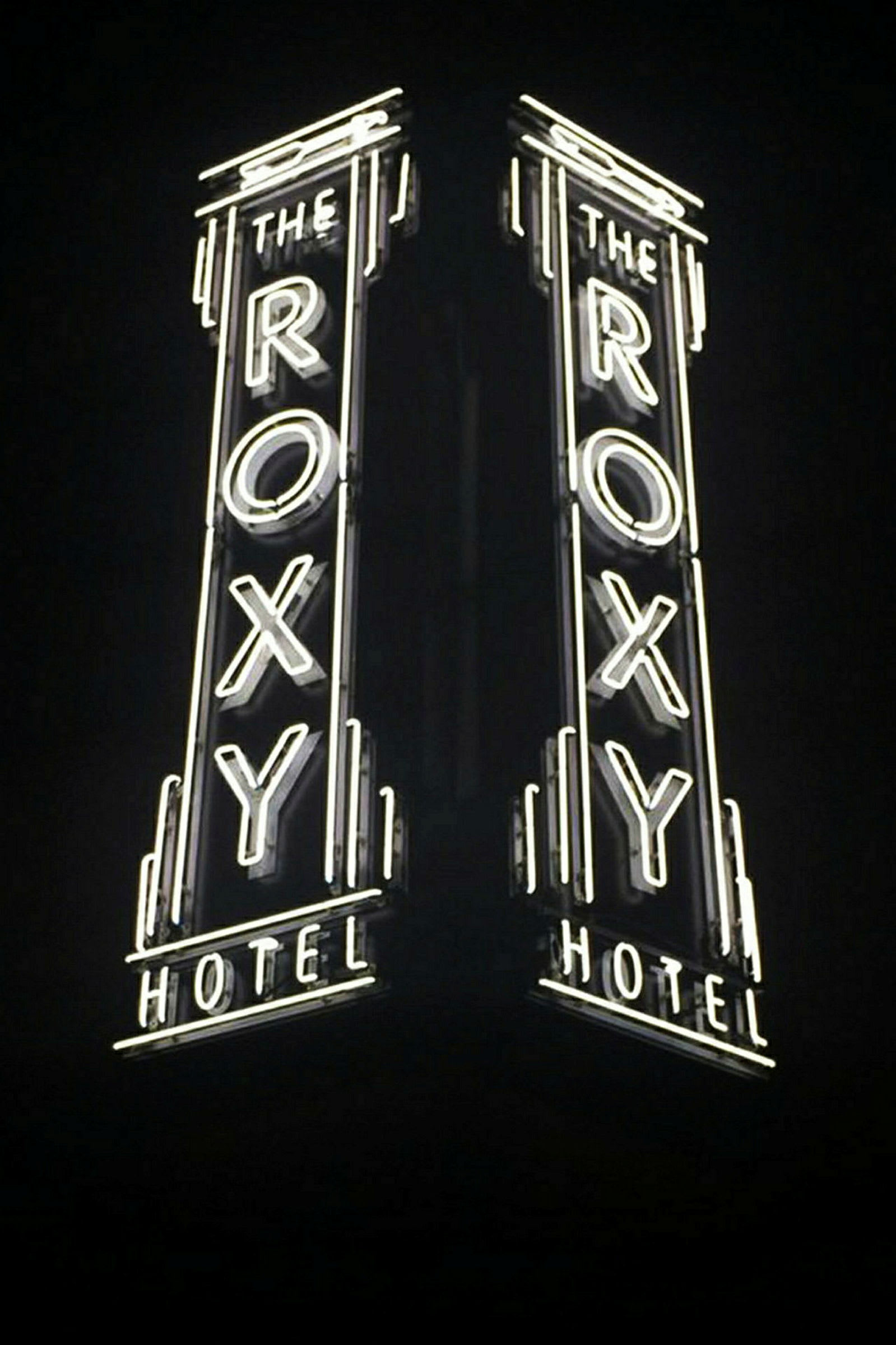 Et neonskilt med teksten "The Roxy Hotel", der lyser i mørket. (AI-genereret tekst)