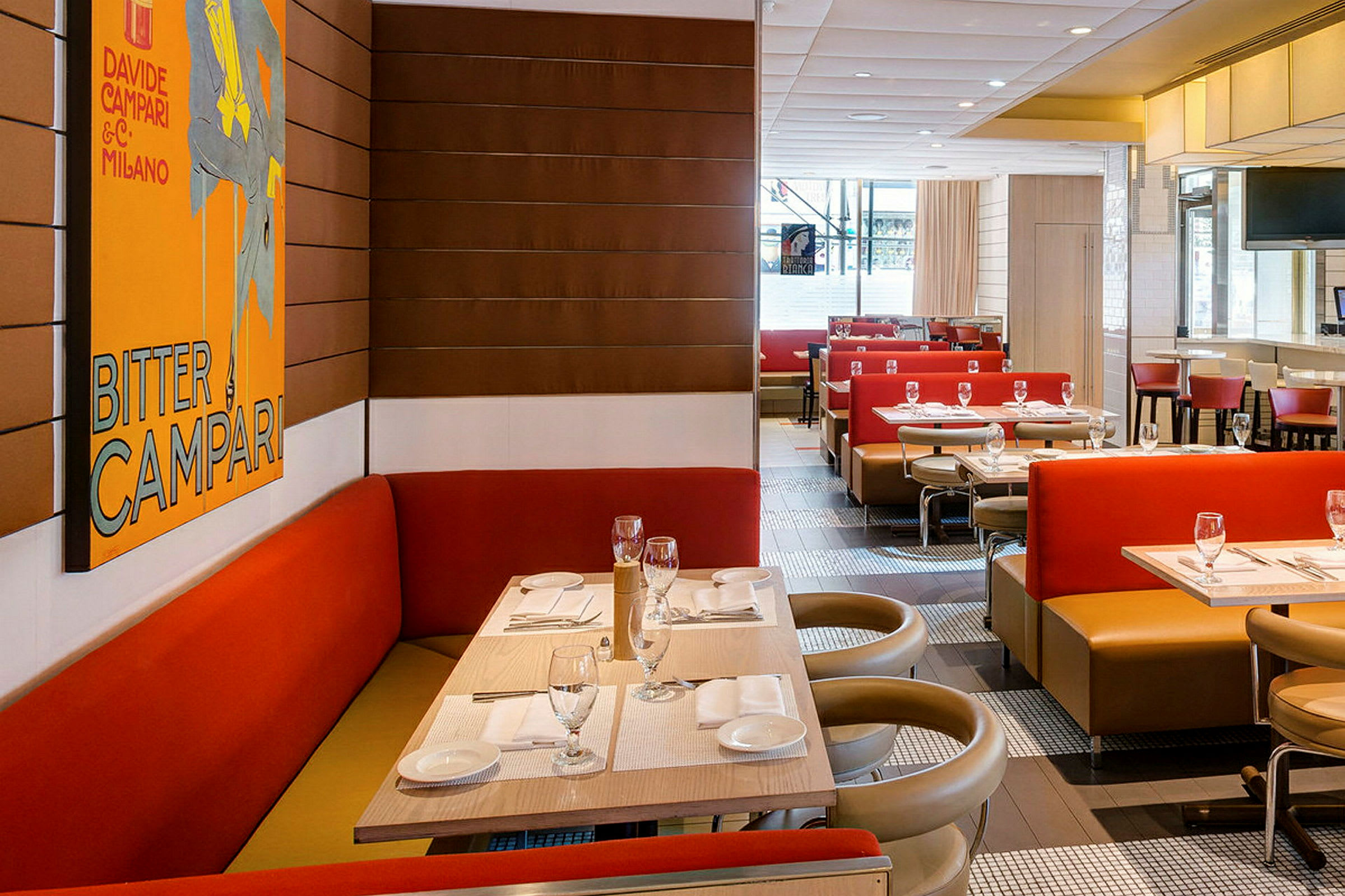 Indretning af en restaurant med røde og beige siddepladser samt et væghængt kunstværk. (AI-genereret tekst)