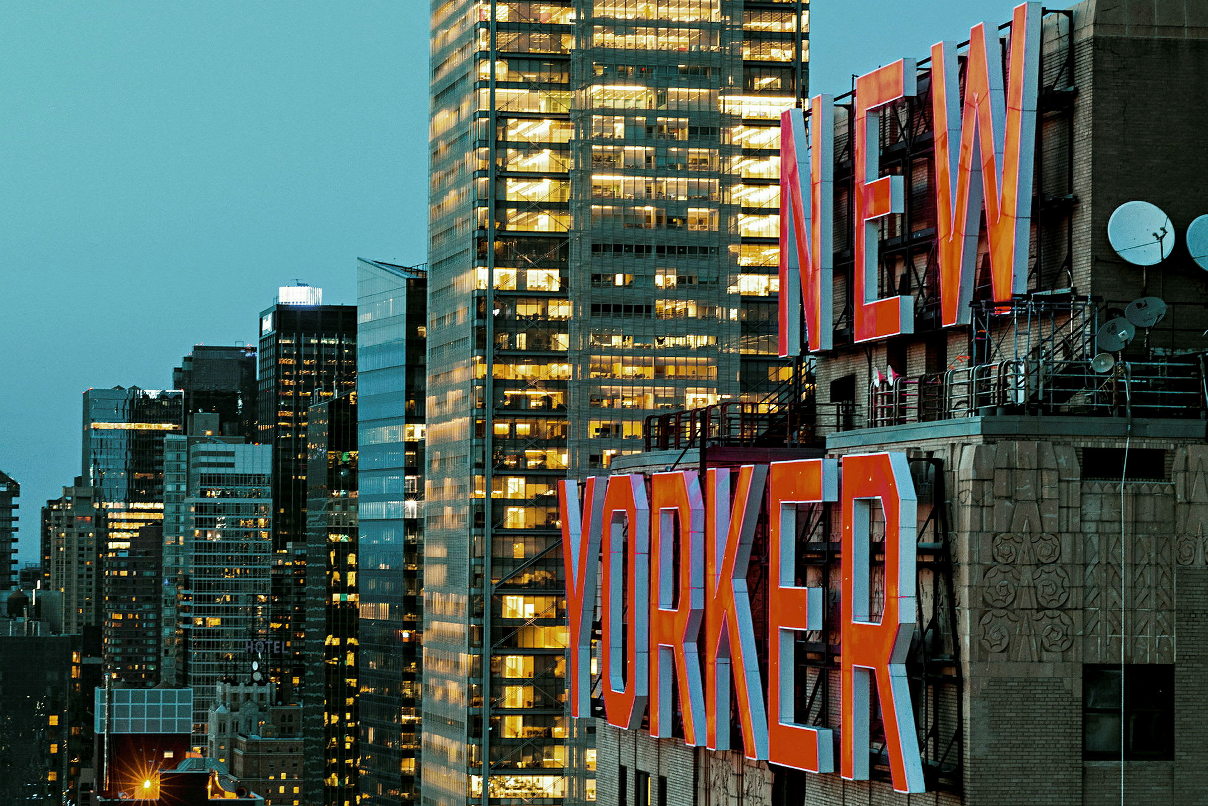 Billede af en bygning med teksten "New Yorker" i store røde bogstaver og flere moderne bygninger i baggrunden. (AI-genereret tekst)