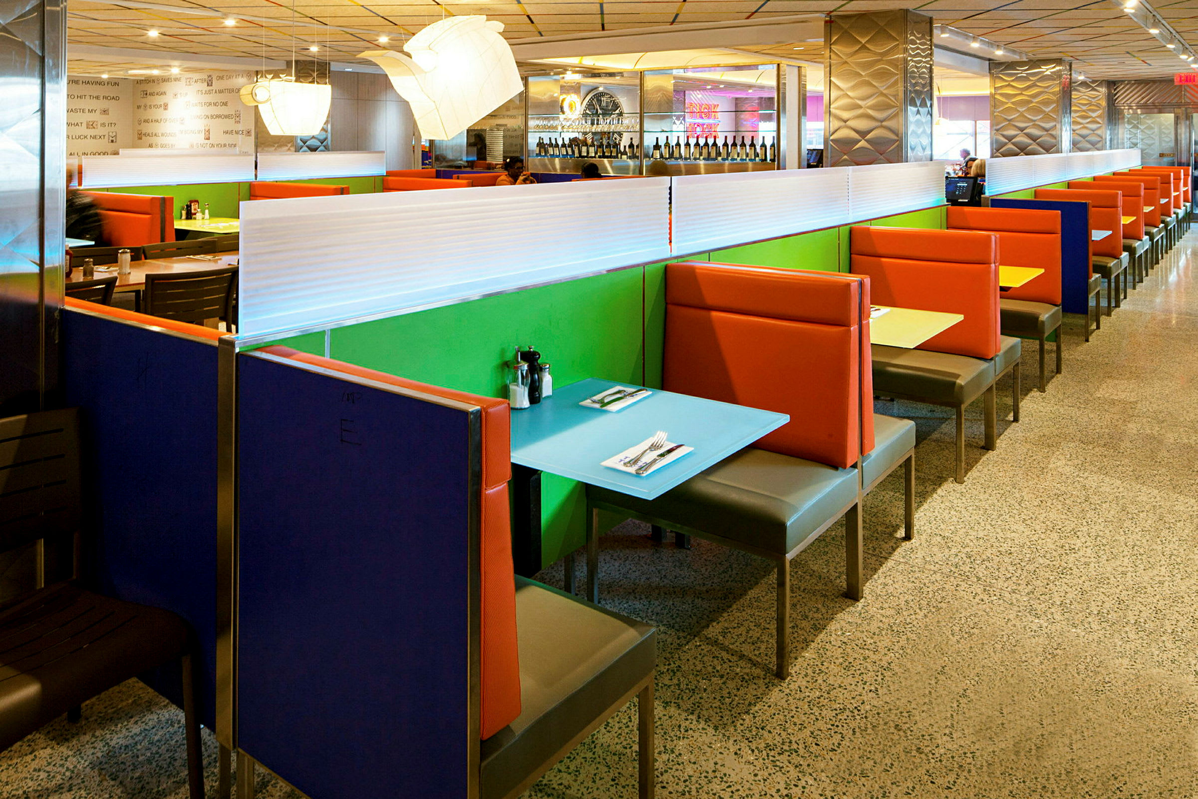 Farverige båse med borde og stole i en restaurant. (AI-genereret tekst)