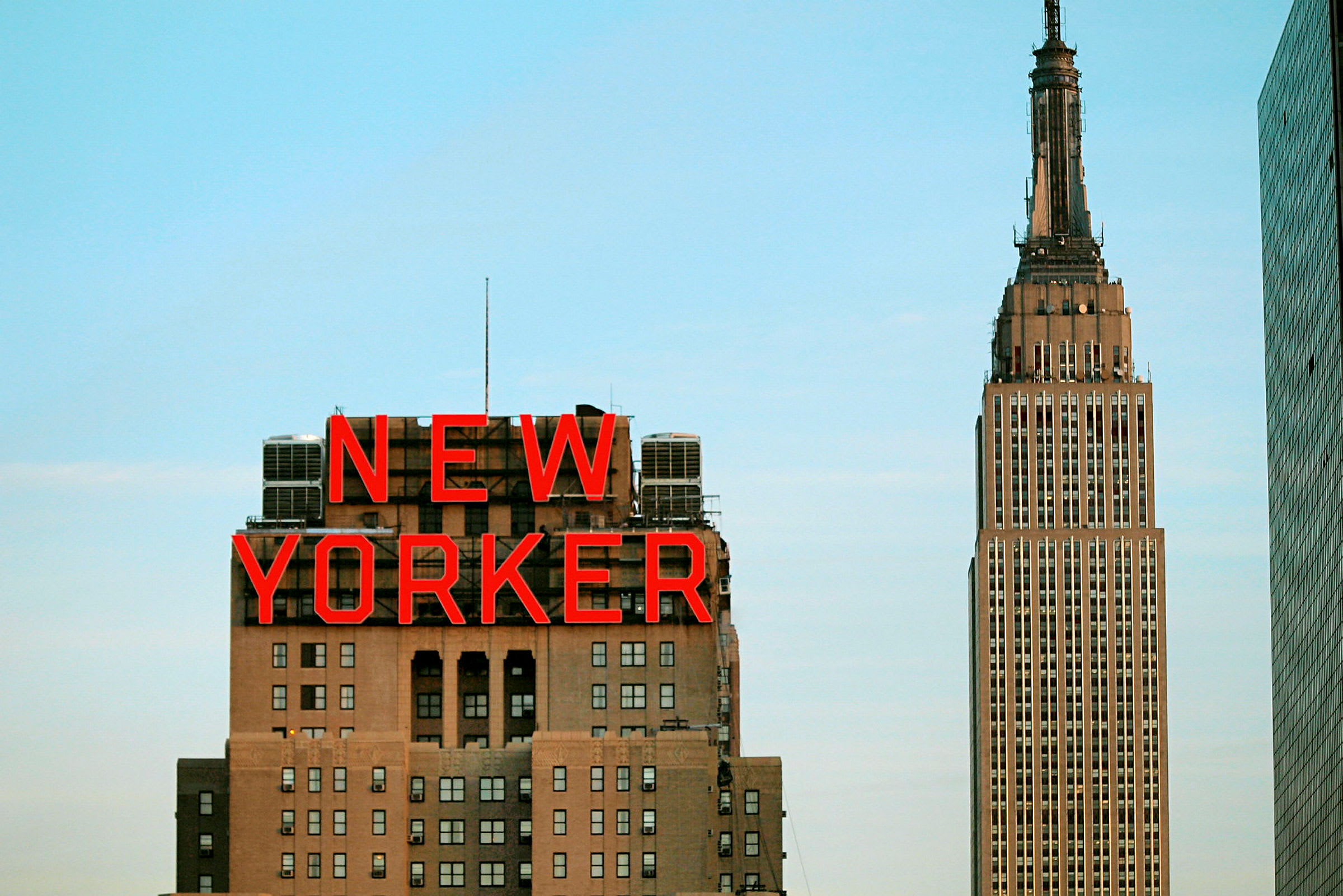 Billede af bygningen med skiltet "New Yorker" og Empire State Building i baggrunden. (AI-genereret tekst)