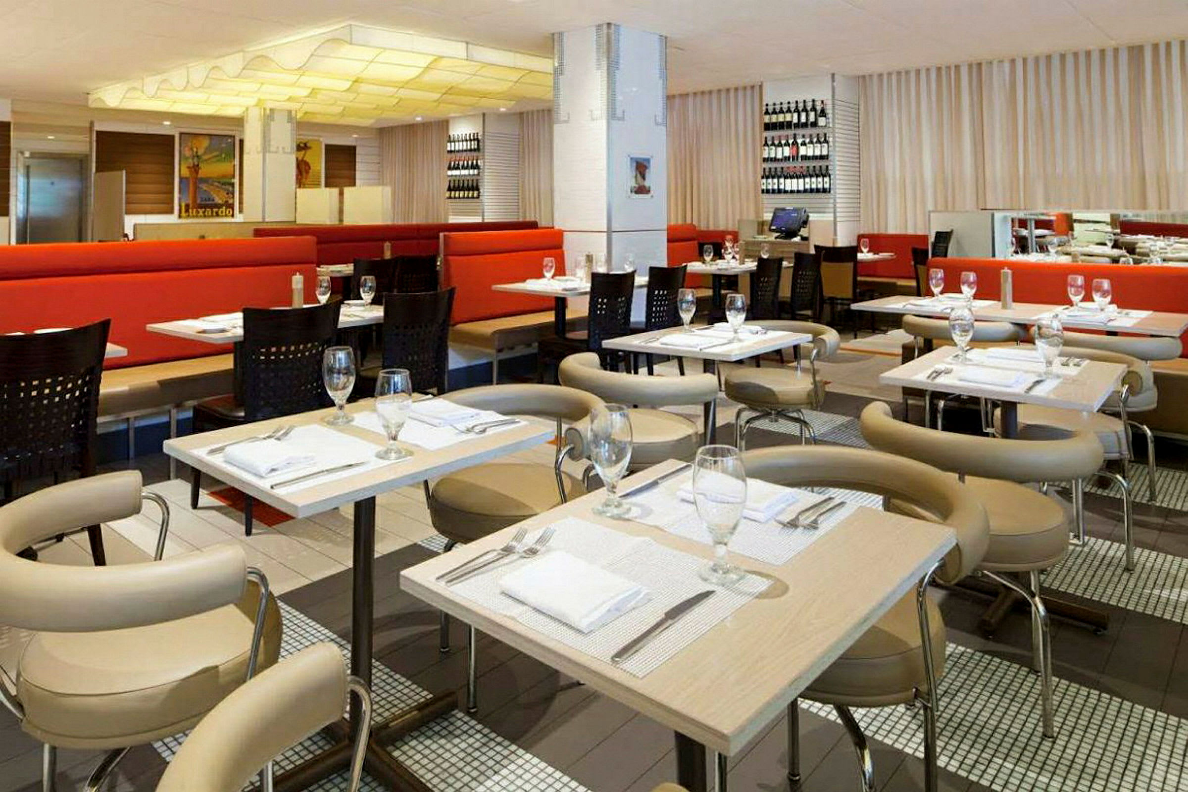 Interiør af en restaurant med dækkede borde og stole, røde sofaer og dekorationer på væggene. (AI-genereret tekst)