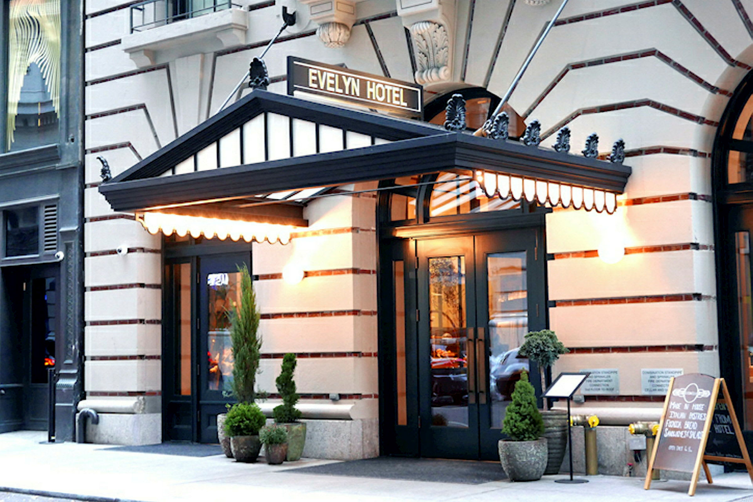 Hotelindgang med en sort baldakin og skiltet "Evelyn Hotel" ovenover. Udenfor står plantekrukker og en menu på et stativ. (AI-genereret tekst)