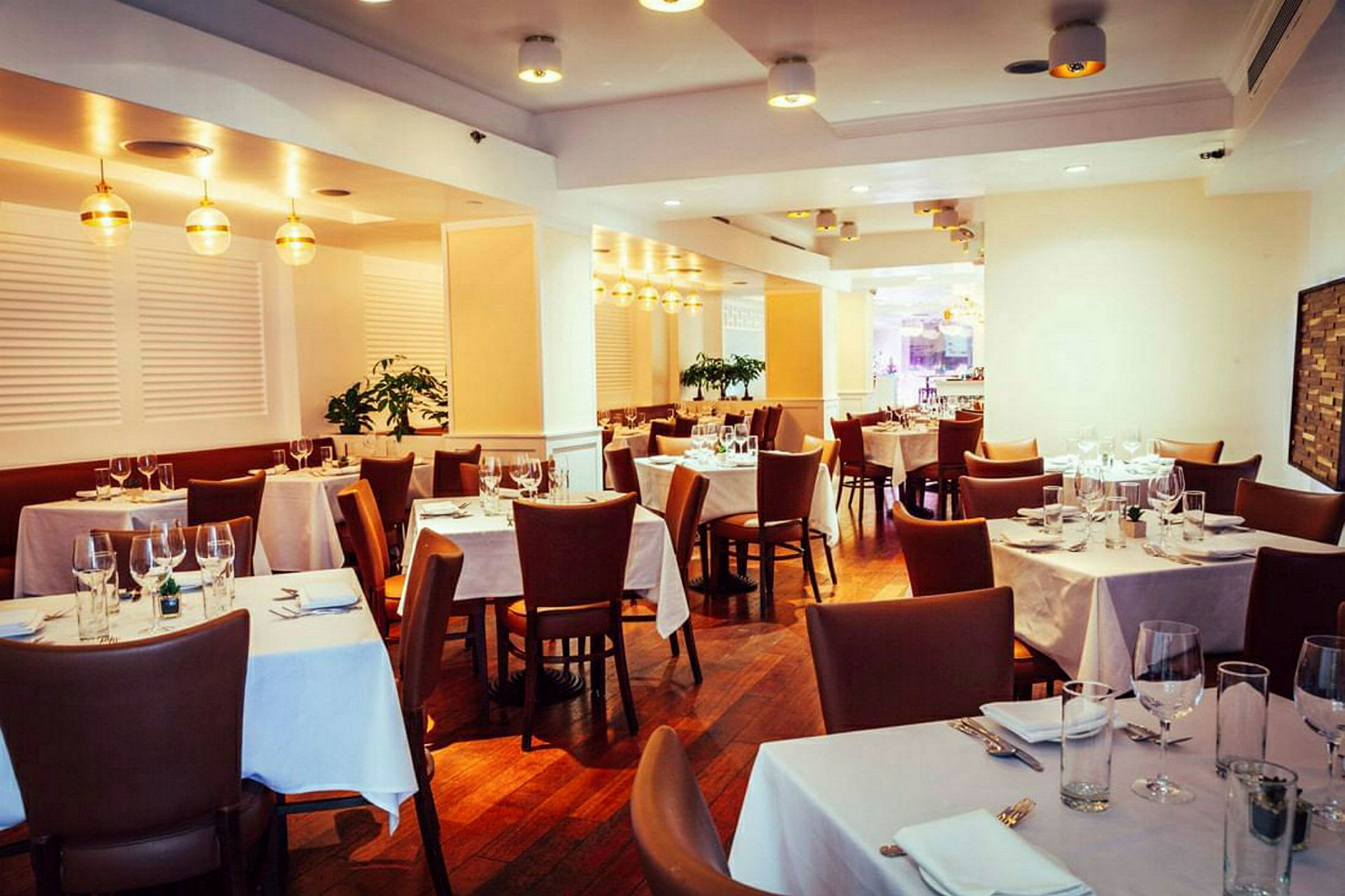 En elegant restaurant med dækkede borde og brune stole. (AI-genereret tekst)