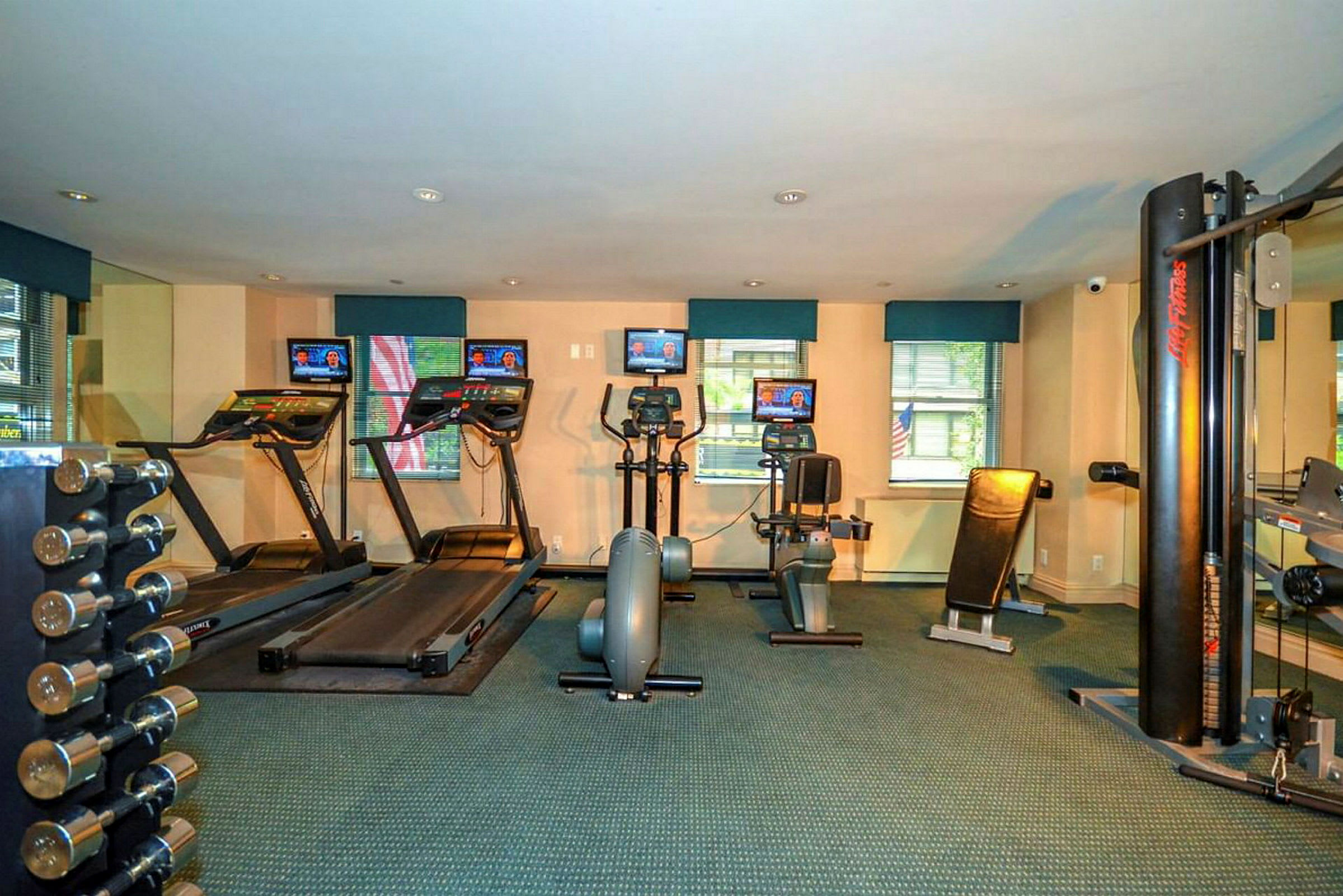 Billede af et fitnesscenter med træningsmaskiner såsom løbebånd, motionscykler og styrketræningsudstyr. (AI-genereret tekst)