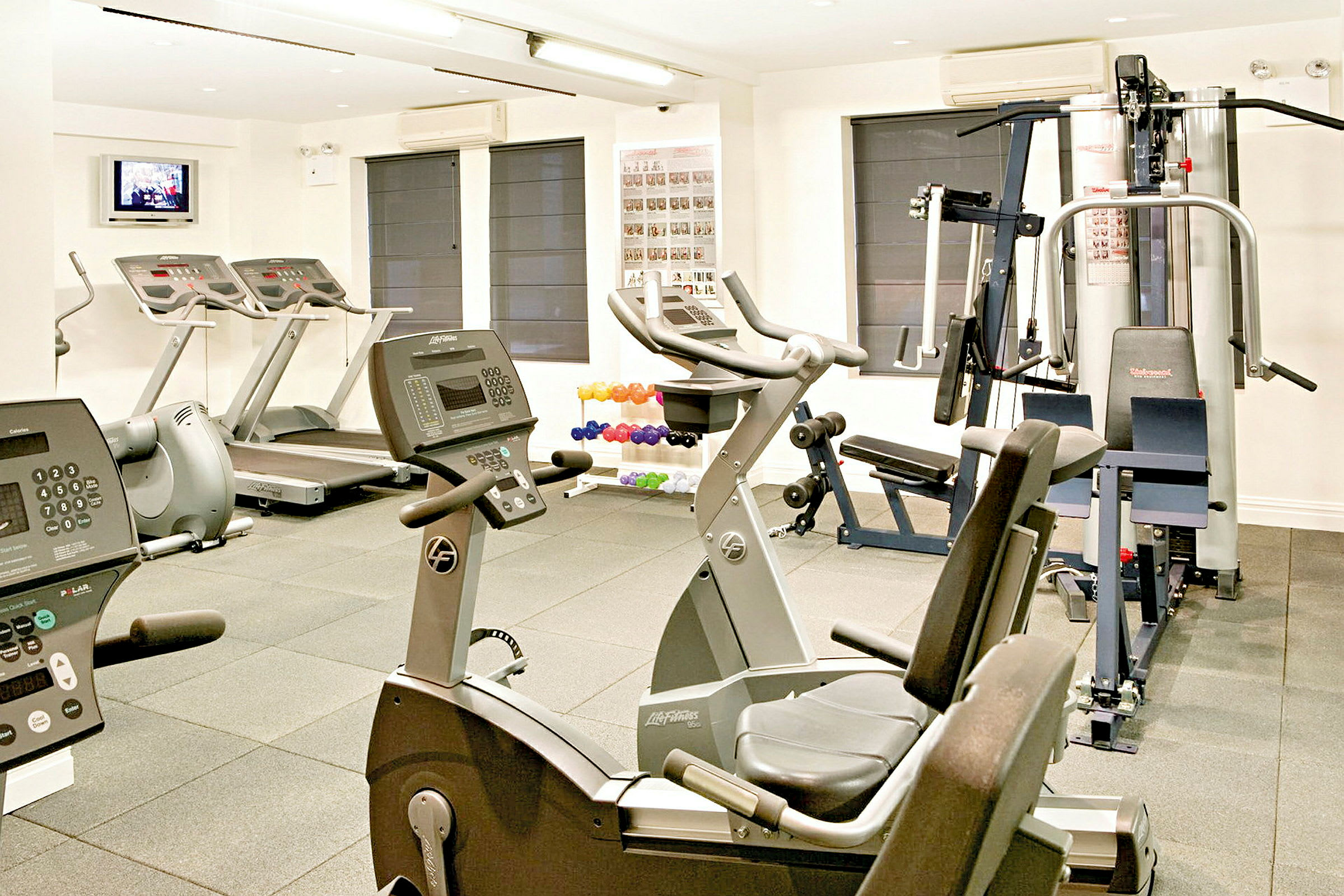 Billede af et fitnessrum med forskellige træningsmaskiner som løbebånd, motionscykler og styrketræningsudstyr. (AI-genereret tekst)