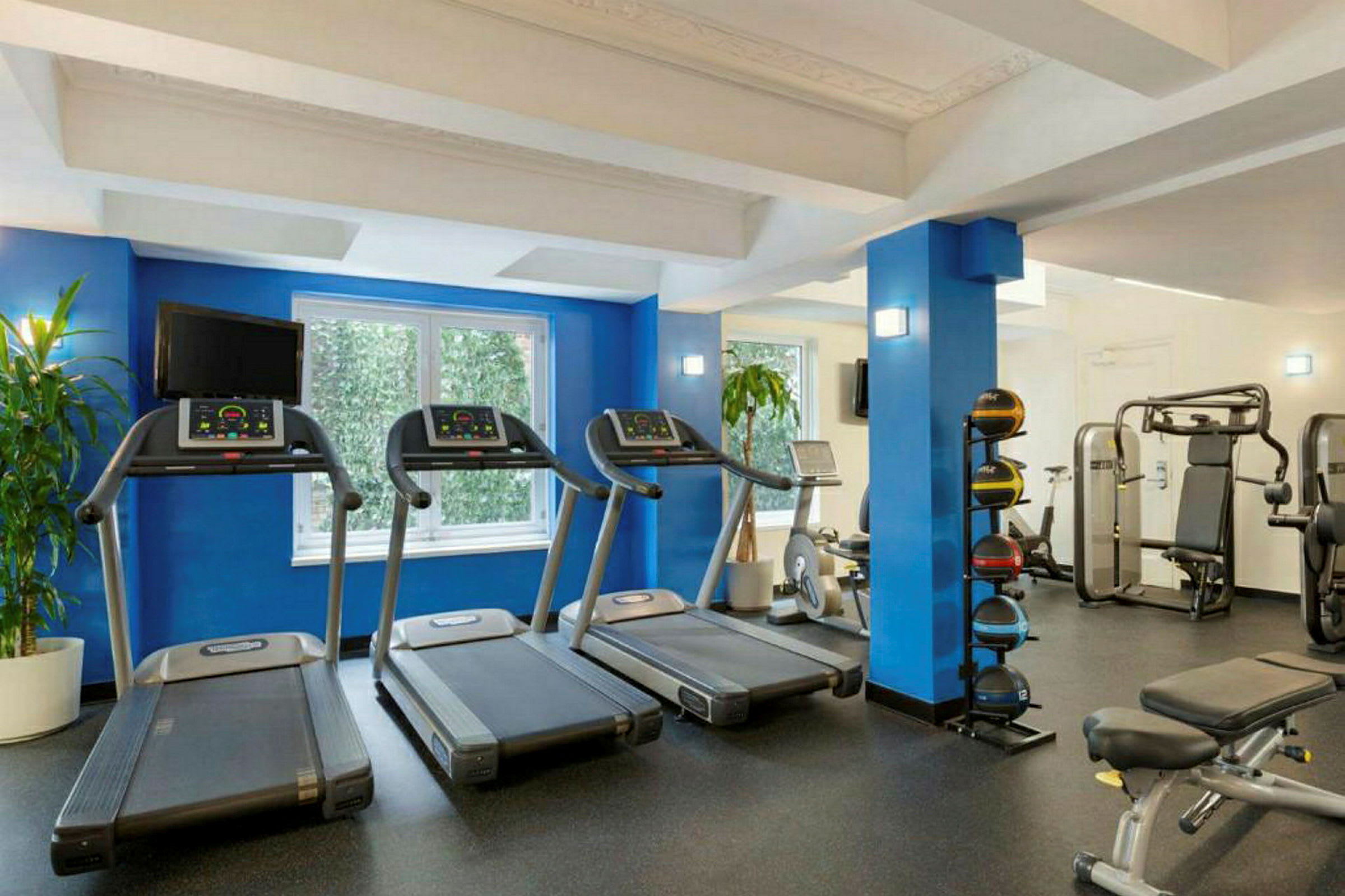 Billede af et lyst fitnesscenter med forskellige træningsmaskiner som løbebånd og træningsbænk. (AI-genereret tekst)