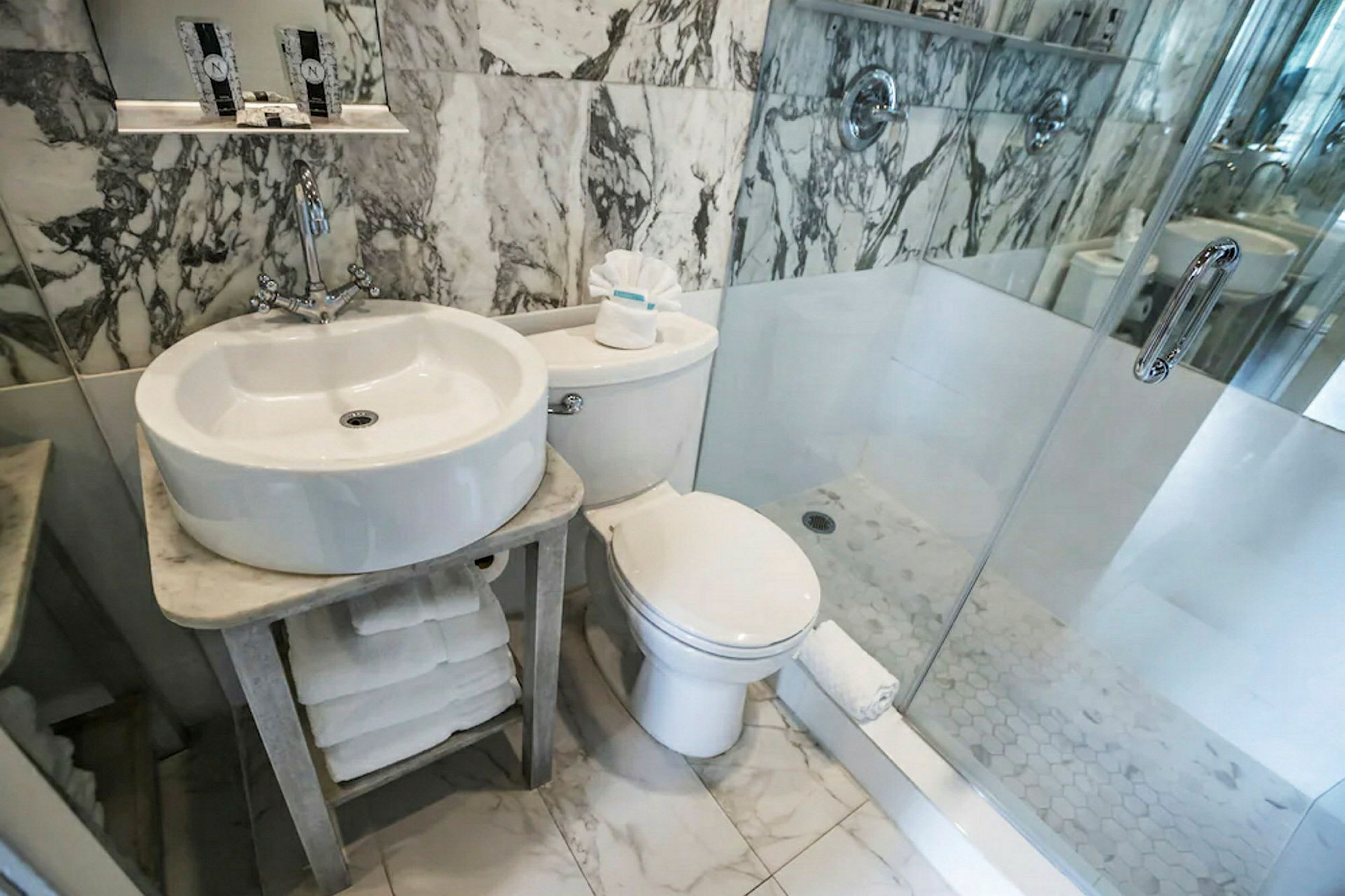 Badeværelse med håndvask, toilet og glasbrusekabine. (AI-genereret tekst)