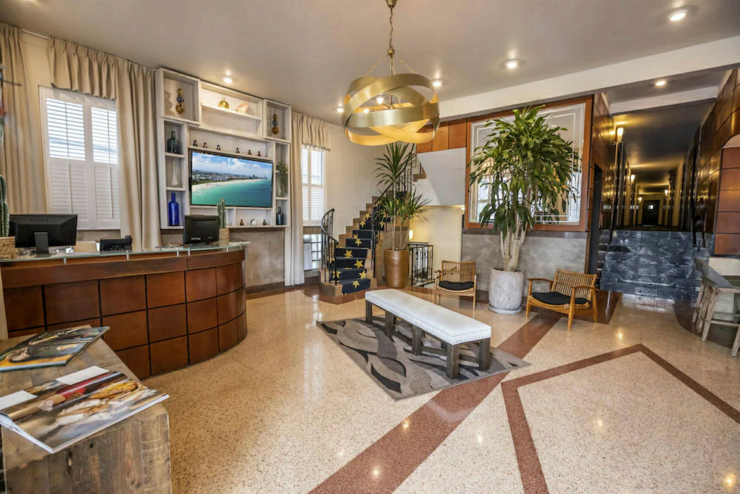 Hotellobby med receptionsdisk, siddeområde og en trappe. (AI-genereret tekst)