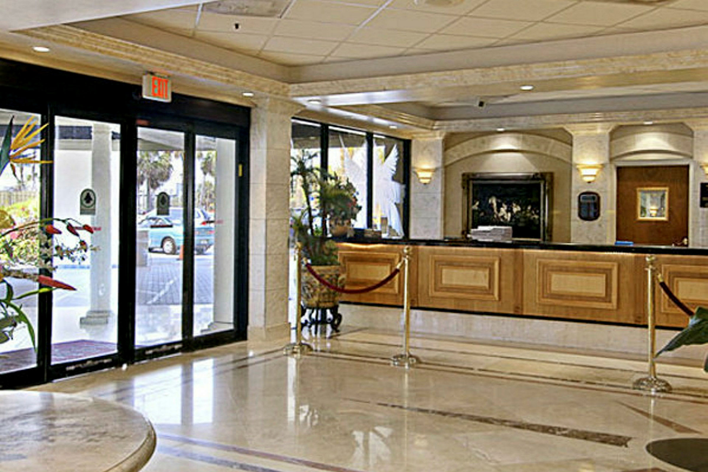 Hotellets foyer med reception og automatiske glasdøre. (AI-genereret tekst)