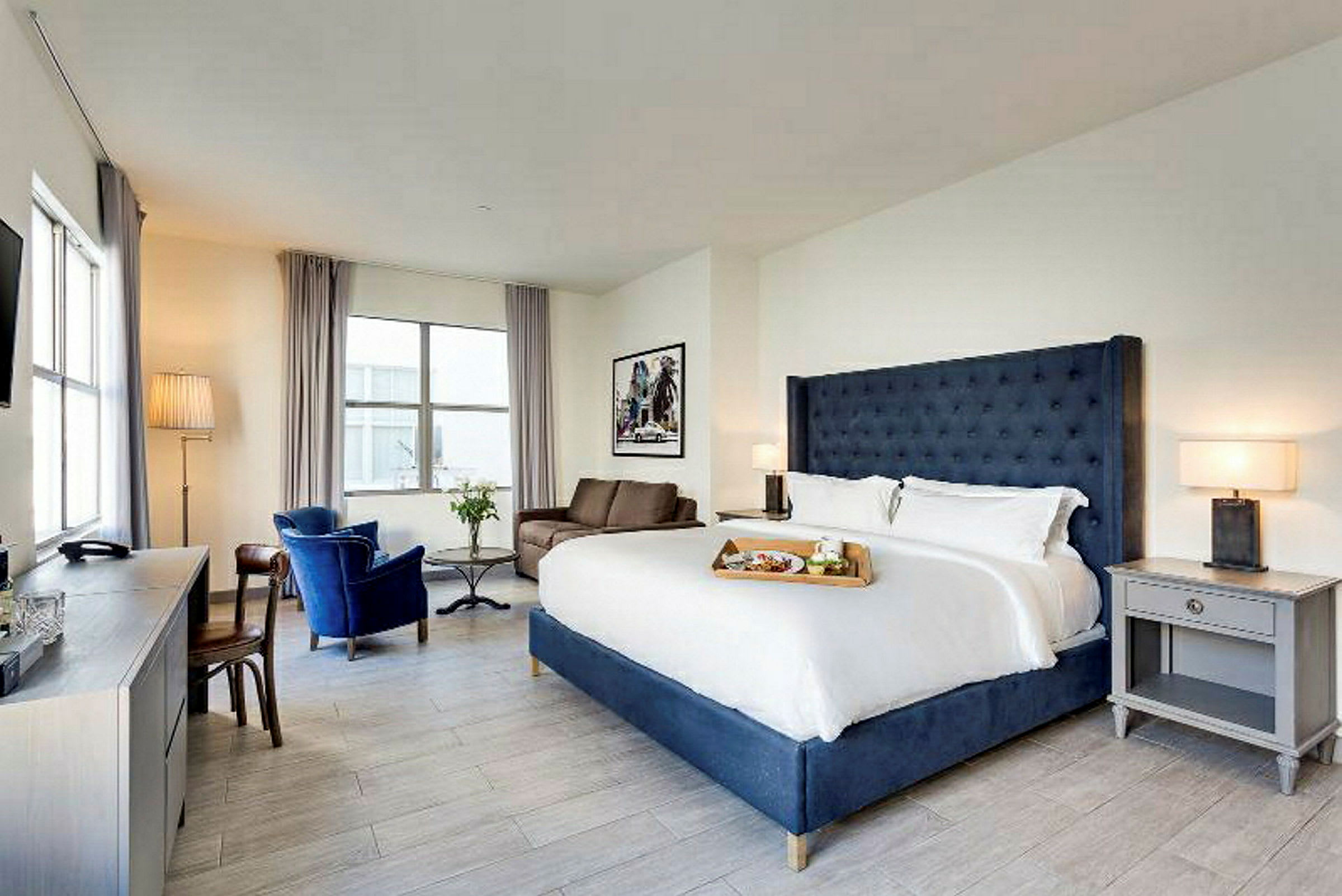 Et lyst hotelværelse med en stor dobbeltseng, lænestole og et skrivebord. (AI-genereret tekst)
