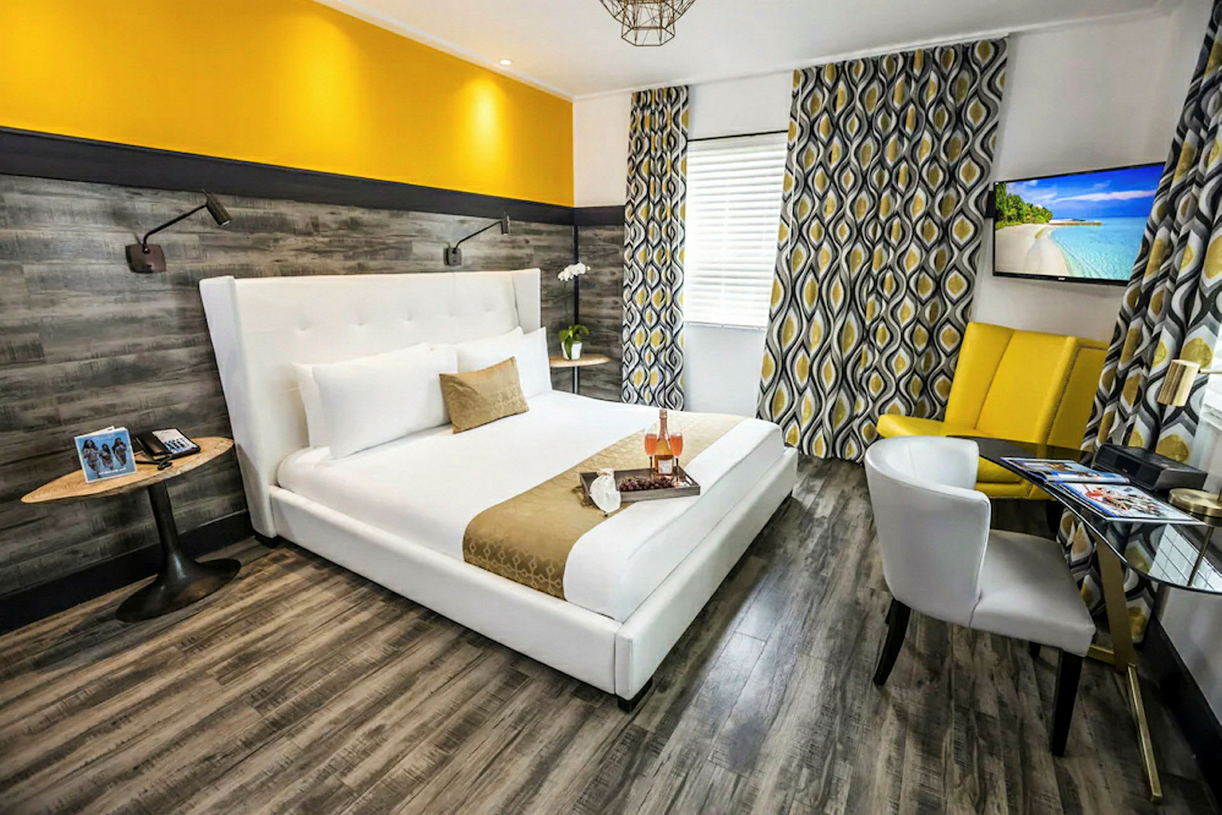 Et moderne hotelværelse med en bred, hvid seng og gule accenter. Væggene har et trælignende mønster, og vinduerne har mønstrede gardiner. (AI-genereret tekst)
