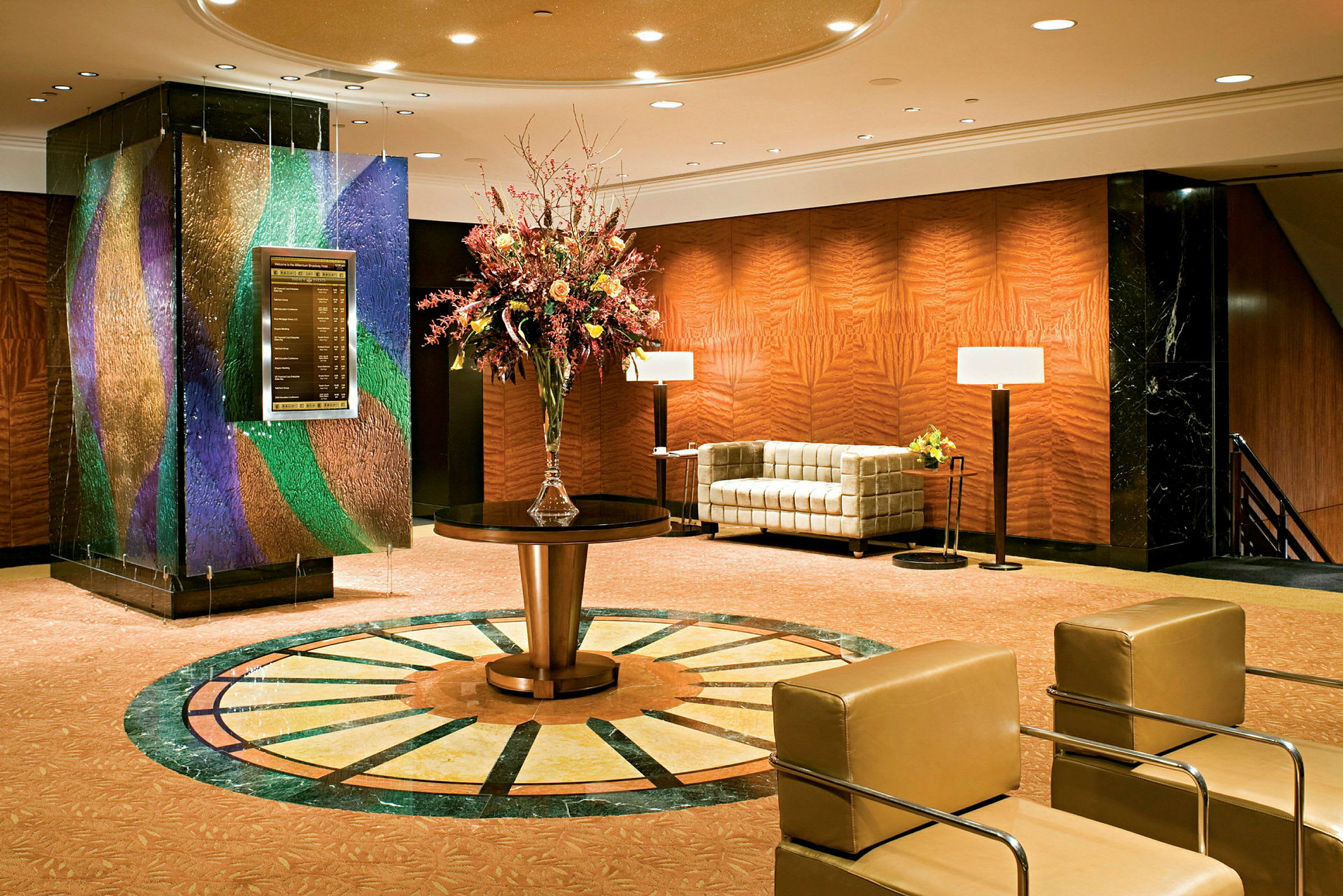Hotellobby med sofaer, bord og en stor blomsterdekoration. (AI-genereret tekst)