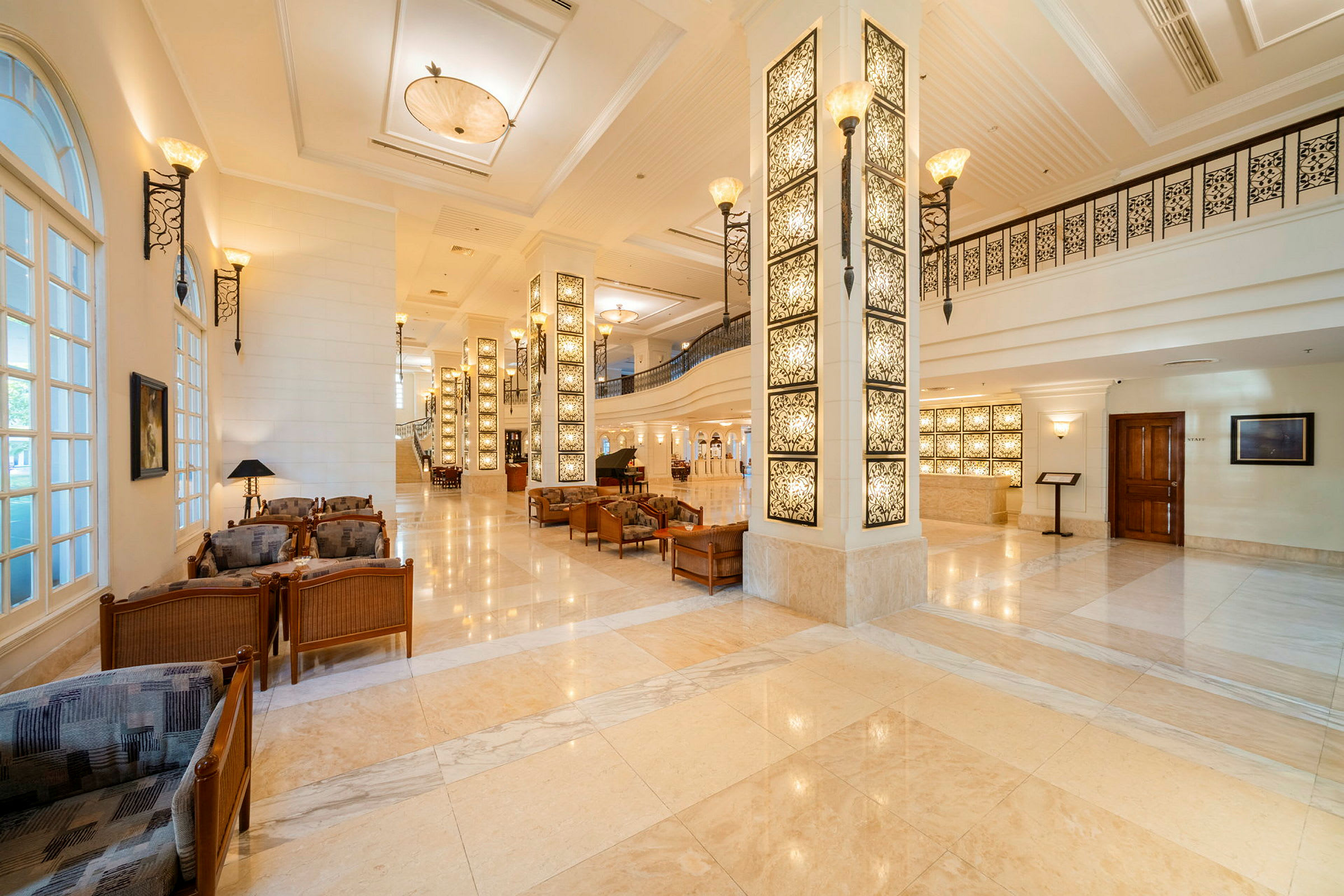 Elegant hotellobby med marmorgulv, dekorative søjler og siddeområder. (AI-genereret tekst)