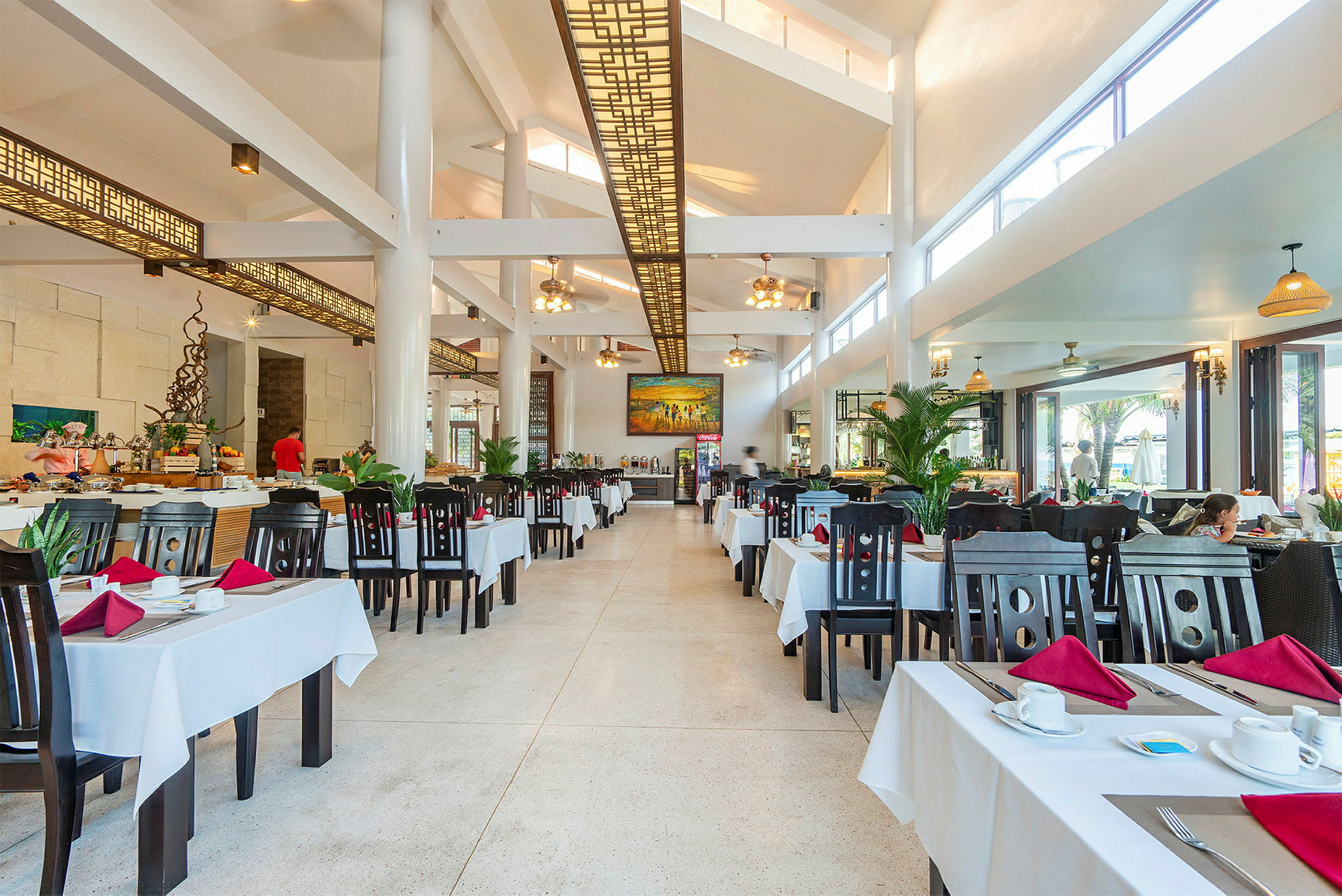 En rummelig restaurant med mange borde dækket med hvide duge. (AI-genereret tekst)