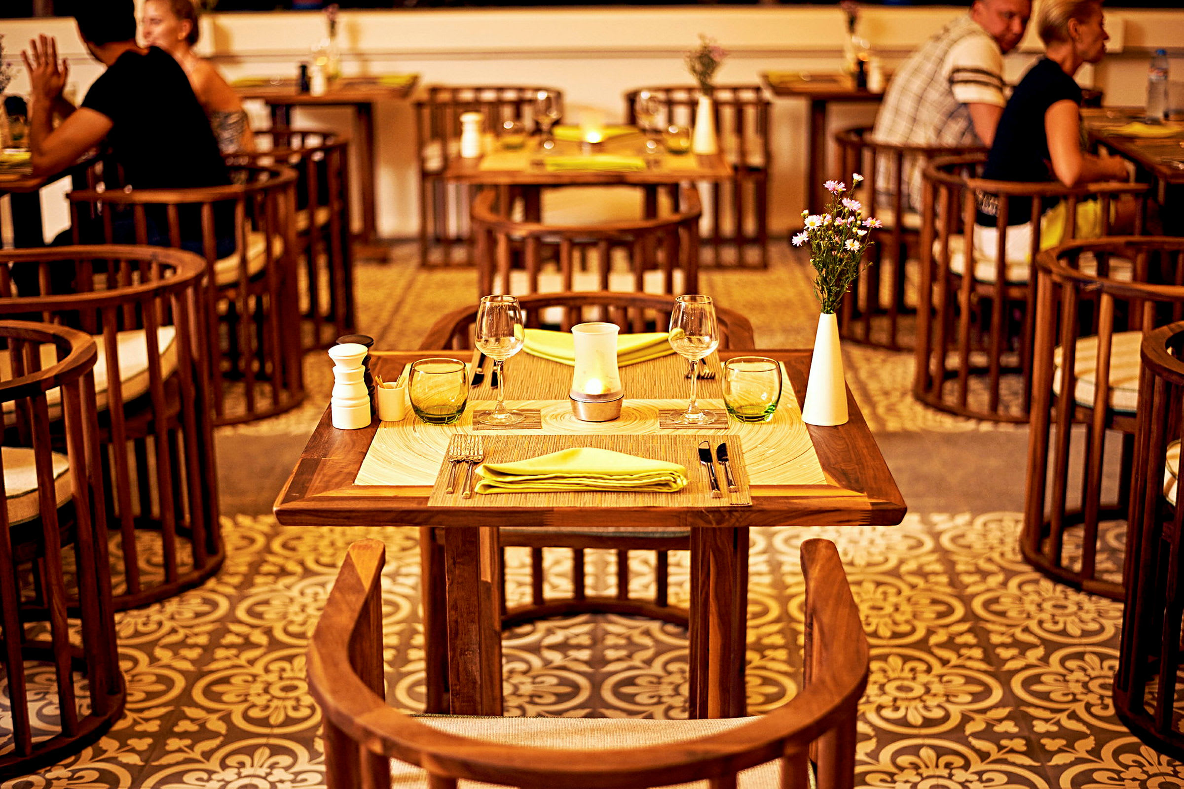 Et dækket bord med dekorationer står i et restaurantområde, omgivet af stole og flere borde. (AI-genereret tekst)