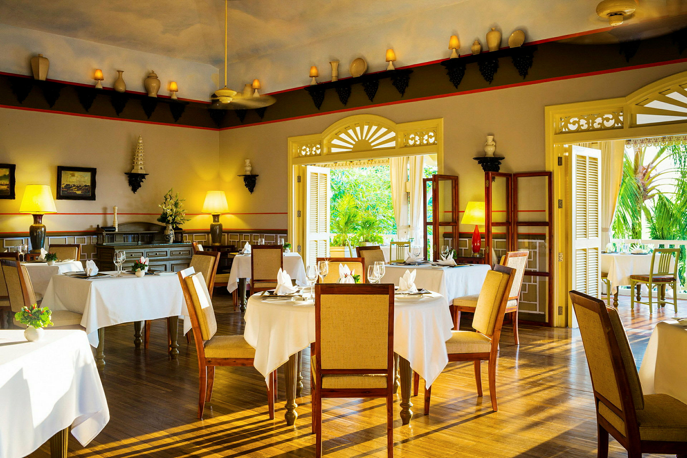 Interiør af en elegant restaurant med borde dækket med hvide duge, træstole og dekorative elementer på væggene. (AI-genereret tekst)
