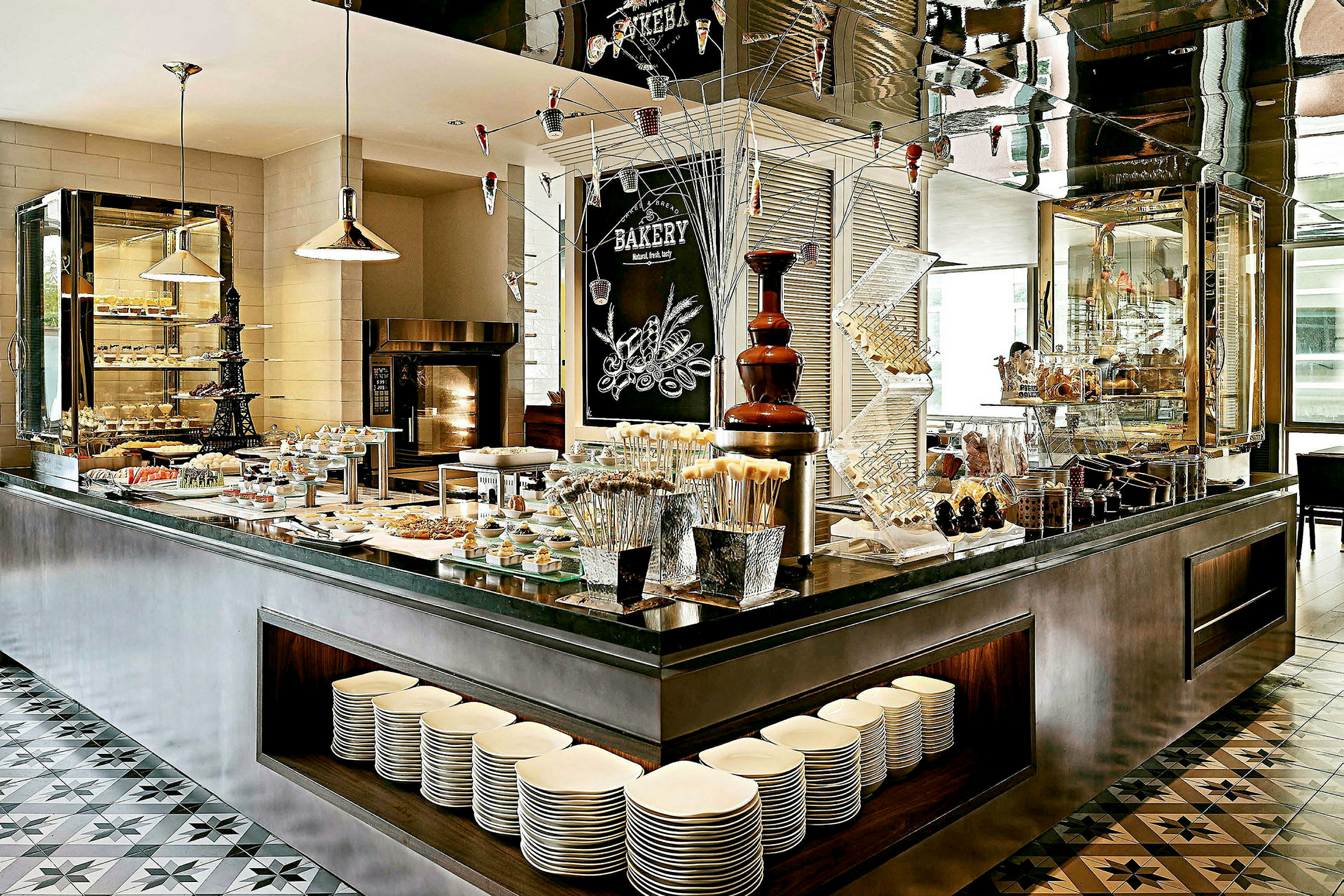 En elegant buffet med forskellige typer mad og desserter, inklusive tallerkener placeret under serveringsbordet. (AI-genereret tekst)