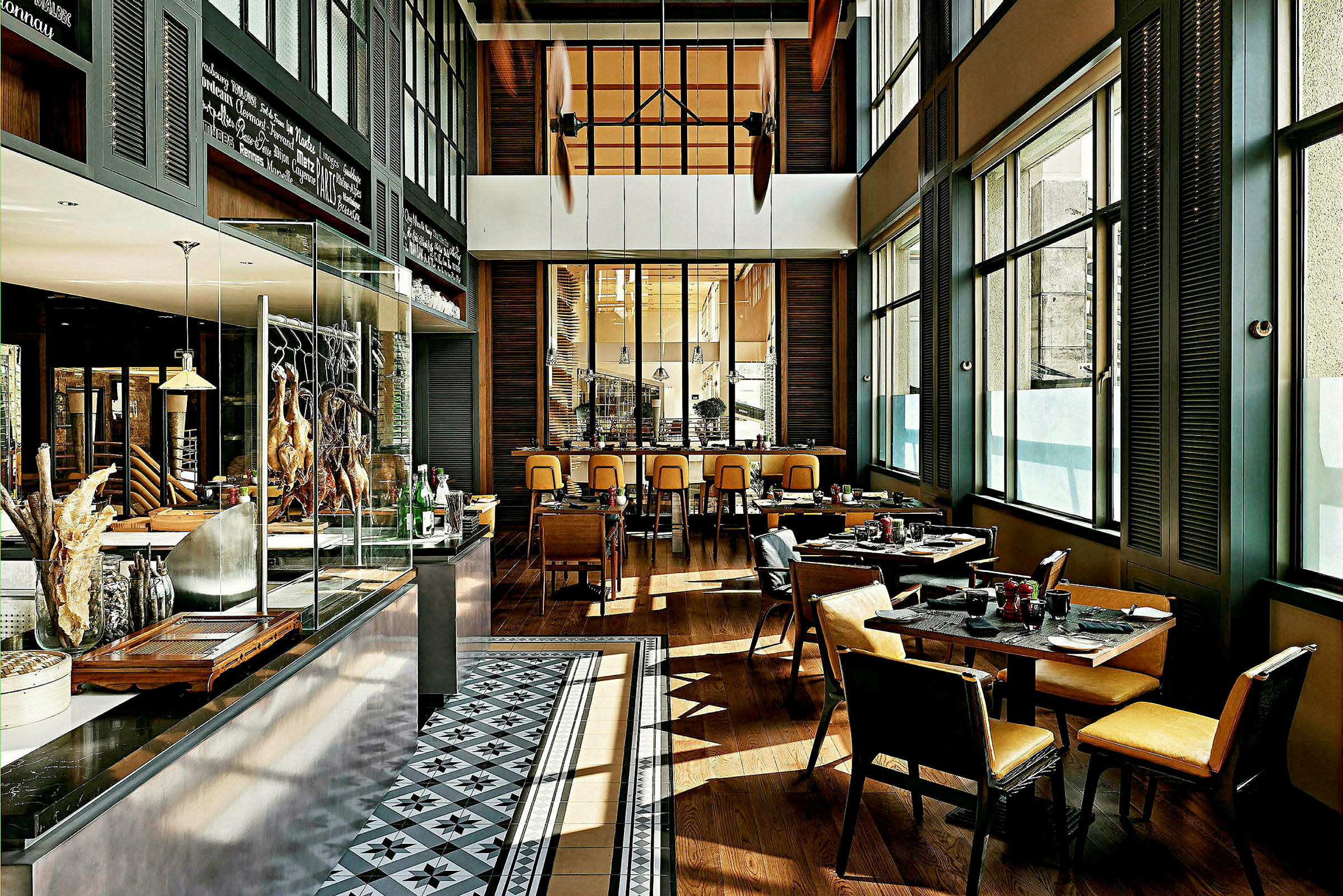 Interiør af en moderne restaurant med borde og stole, store vinduer og et åbent køkkenområde. (AI-genereret tekst)