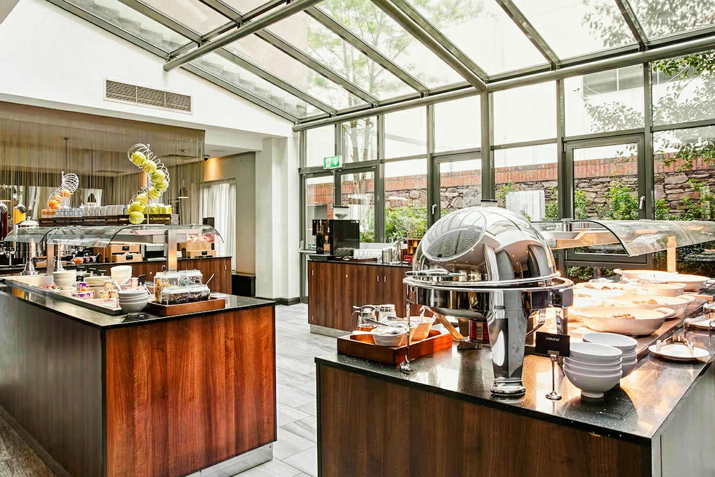 En moderne buffet med mad, frugt og drikke indendørs med store vinduer. (AI-genereret tekst)