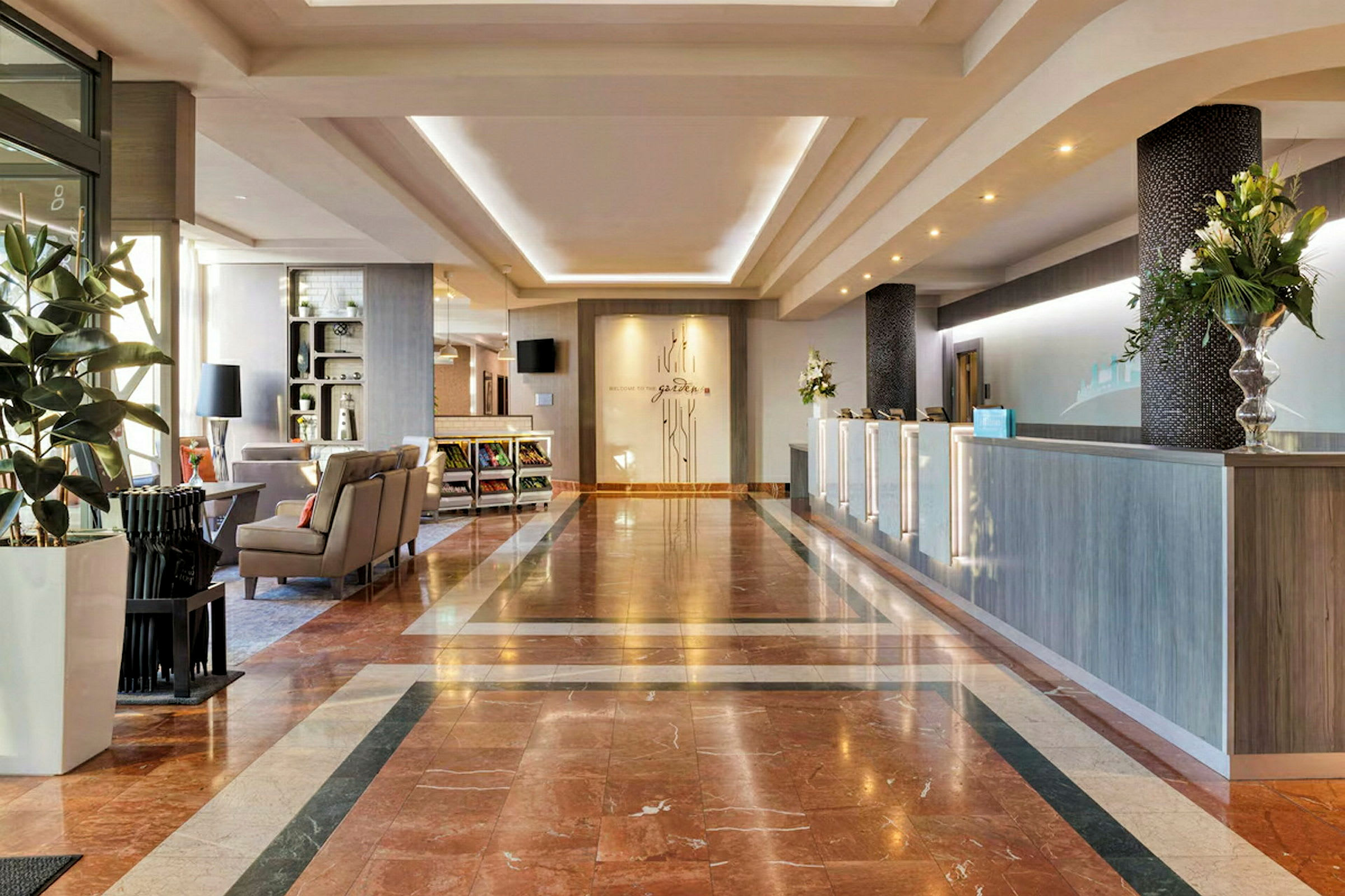 Hotellets lobby med marmorgulv, reception og siddeområde. (AI-genereret tekst)