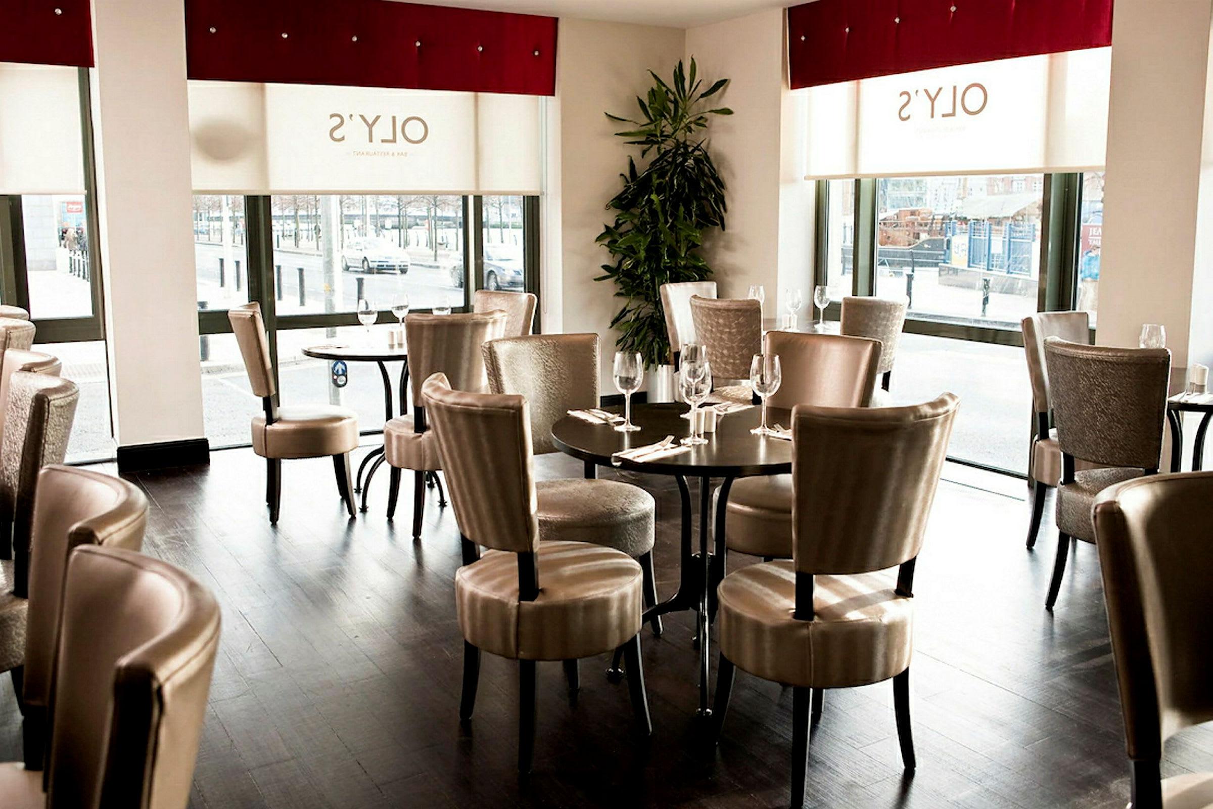Indendørs i en restaurant med borde og stole samt store vinduer. (AI-genereret tekst)